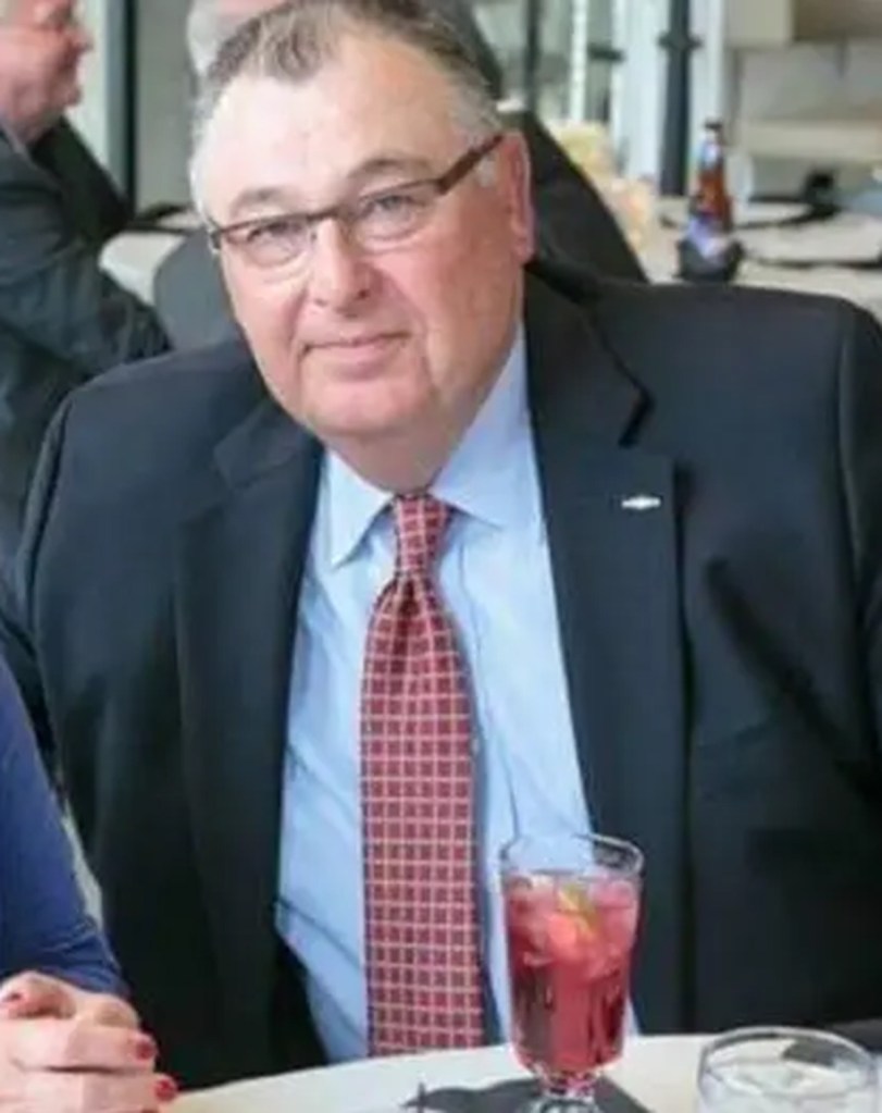 John Bond, a man in a suit and tie, seated at a table.