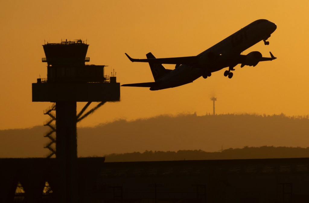 Passenger plane takes off from Frankfurt Airport at dusk, passing the tower of German Air Traffic Control.