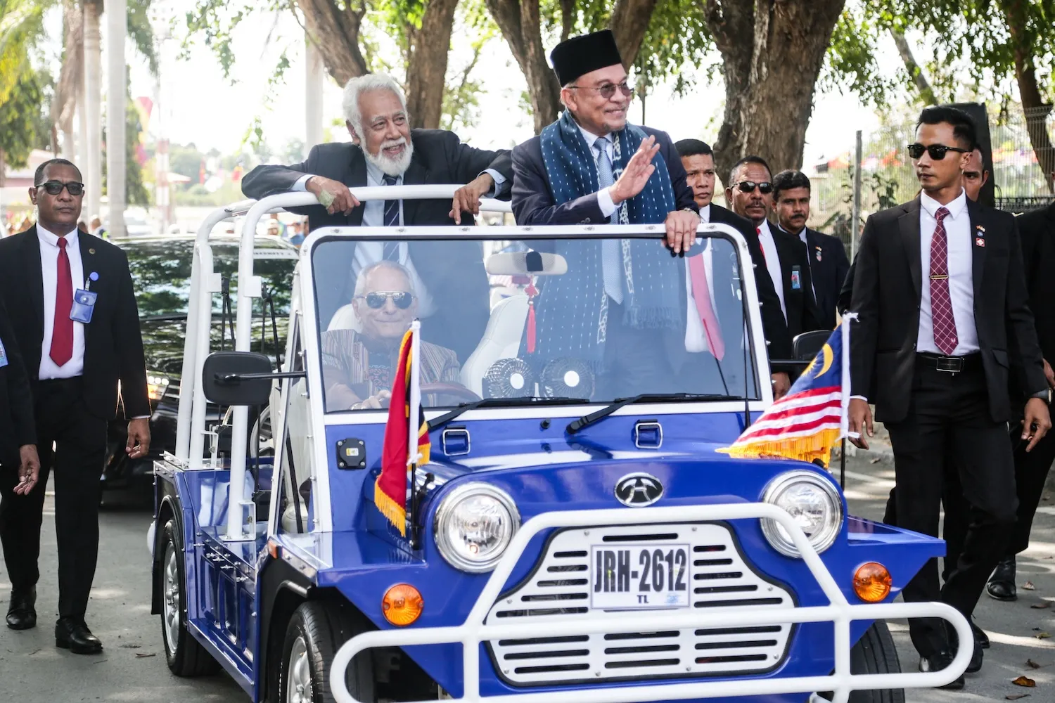 Malaysian Prime Minister Anwar Ibrahim (right, front seat) waves from an open-top car owned and driven by Timorese President Jose Ramos-Horta as Timorese Prime Minister Xanana Gusmao (left, backseat) looks on, in Dili, East Timor, on Sept. 23.