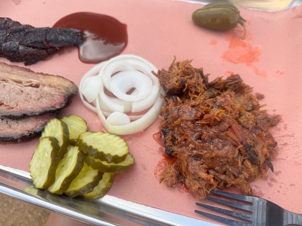 Brisket, pulled pork, onions, pickles on pink paper on tray