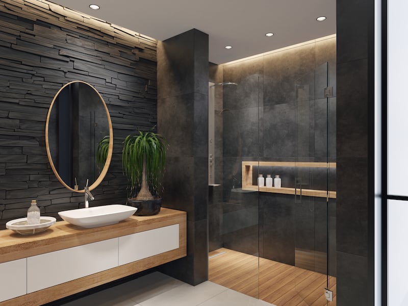 Minimalist bathroom with two round mirrors and wooden frame.
natural stacked black matte stone wall with large black matte tiles.