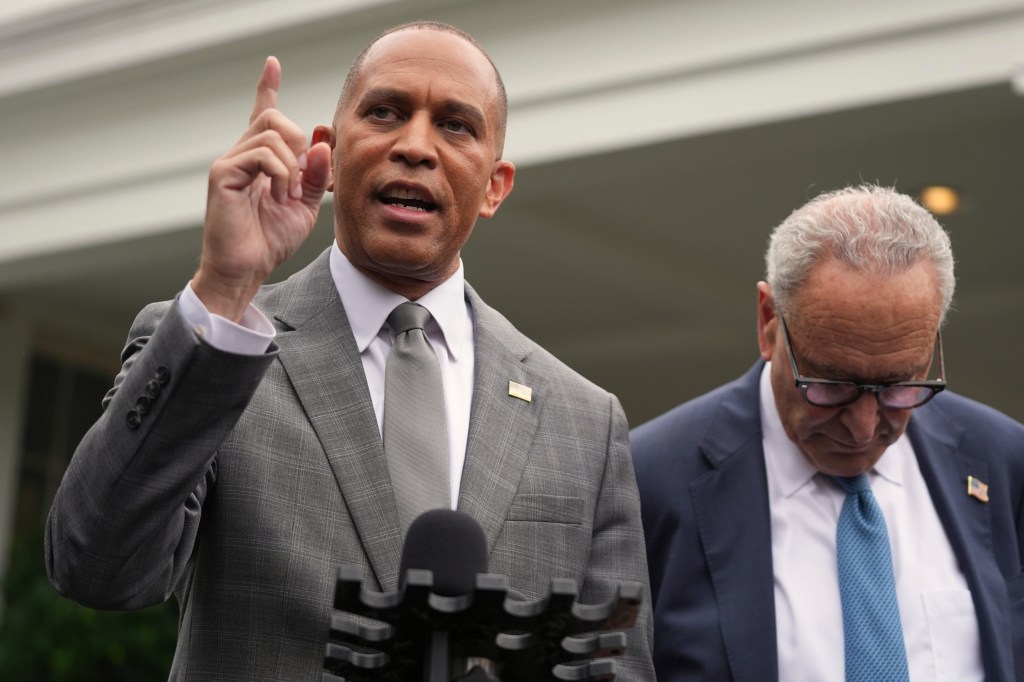 House Minority Leader Hakeem Jeffries speaks at a press conference next to Senate Minority Leader Chuck Schumer, both wearing suits and American flag pins.