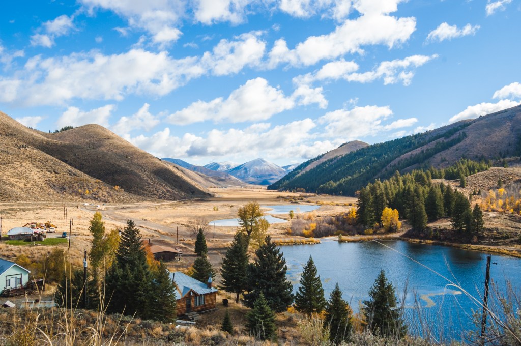 Partly cloudy blue sky over mountain landscape, lakes, and countryside properties in Deer Creek in Hailey, Idaho.