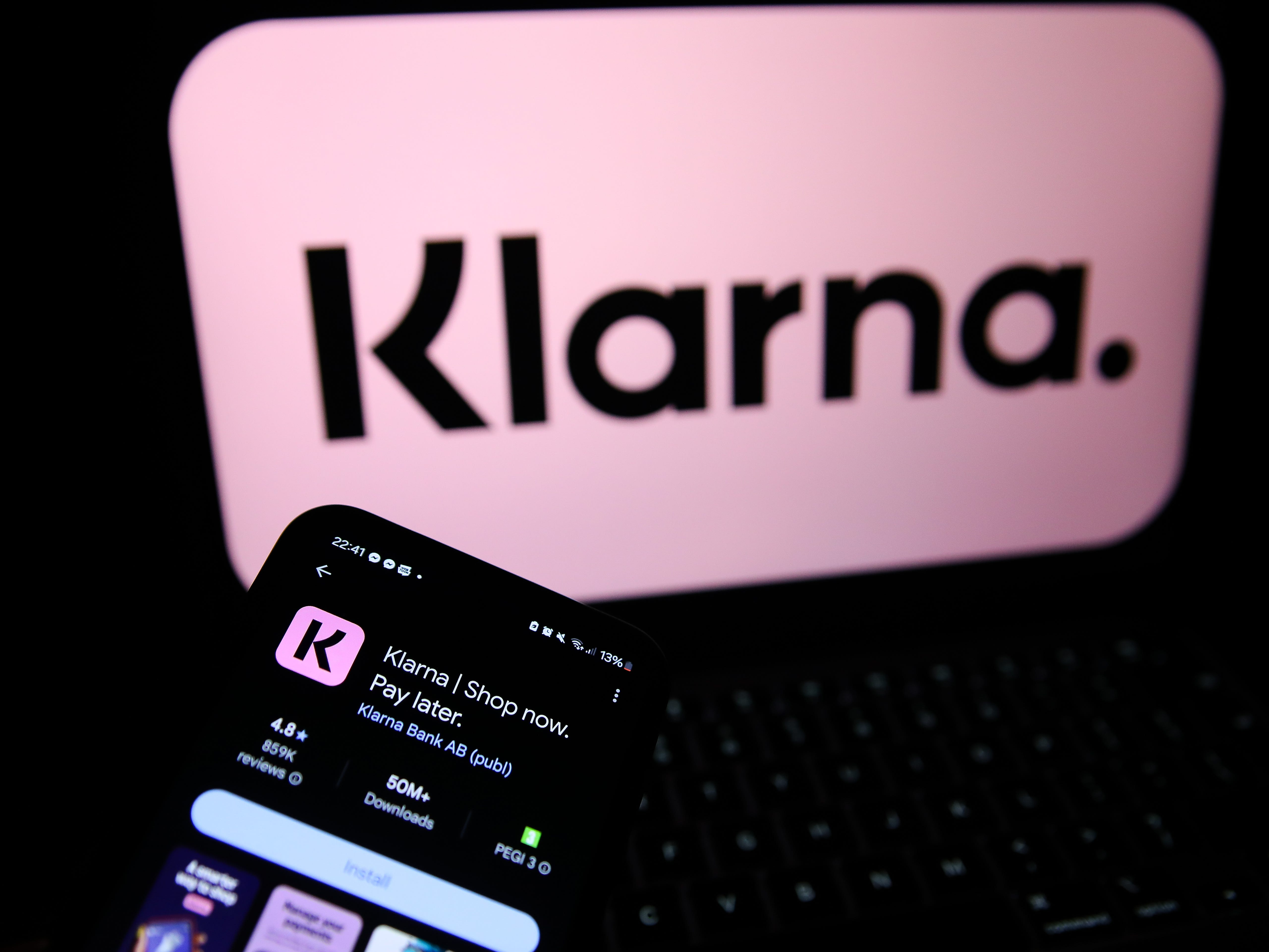 Klarna logo behind an iPhone with the Klarna app on App Store.