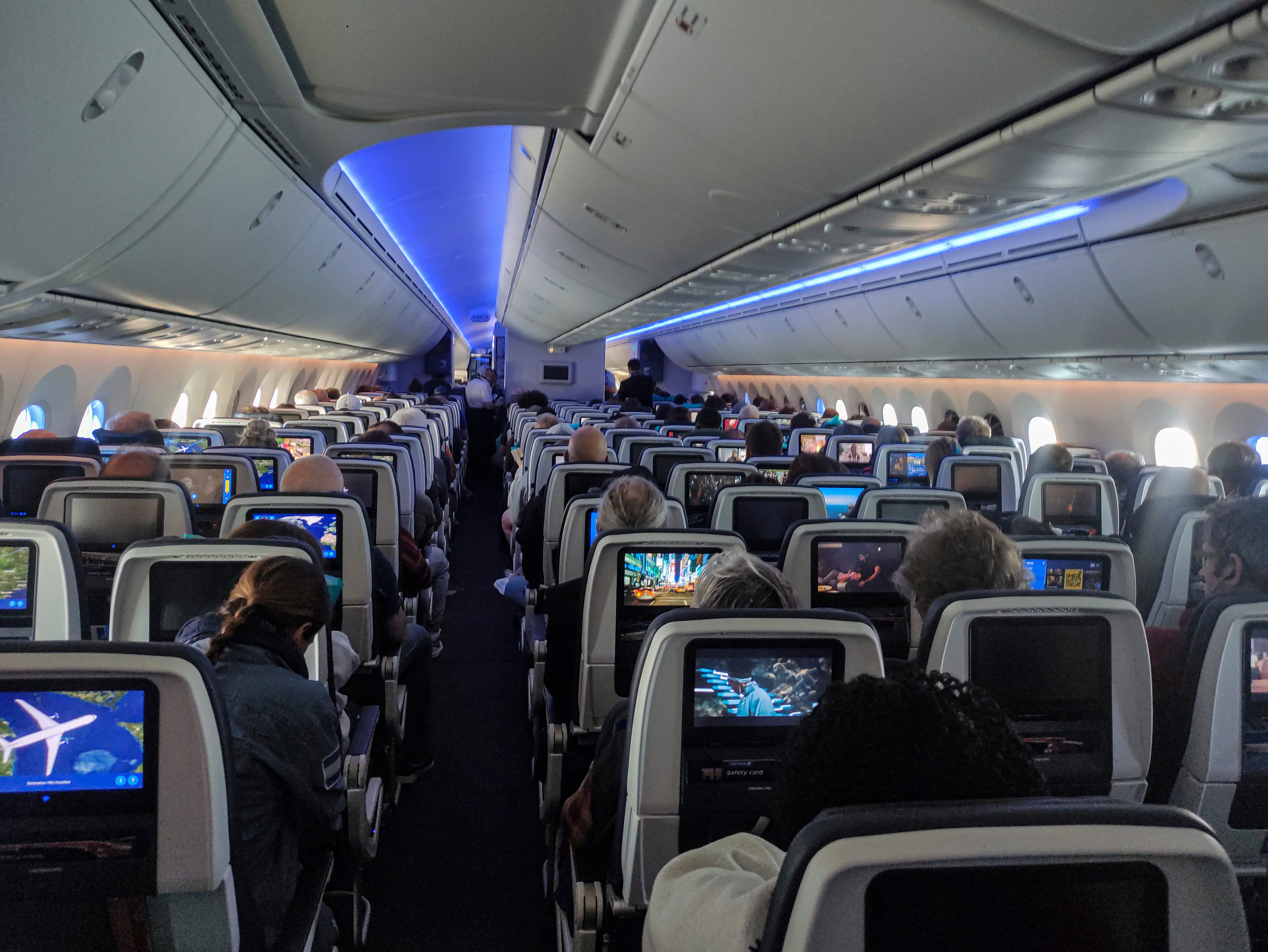 Cabin view of the economy section with the personal screens of the in flight entertainment system. United Airlines Boeing 787 Dreamliner aircraft interior