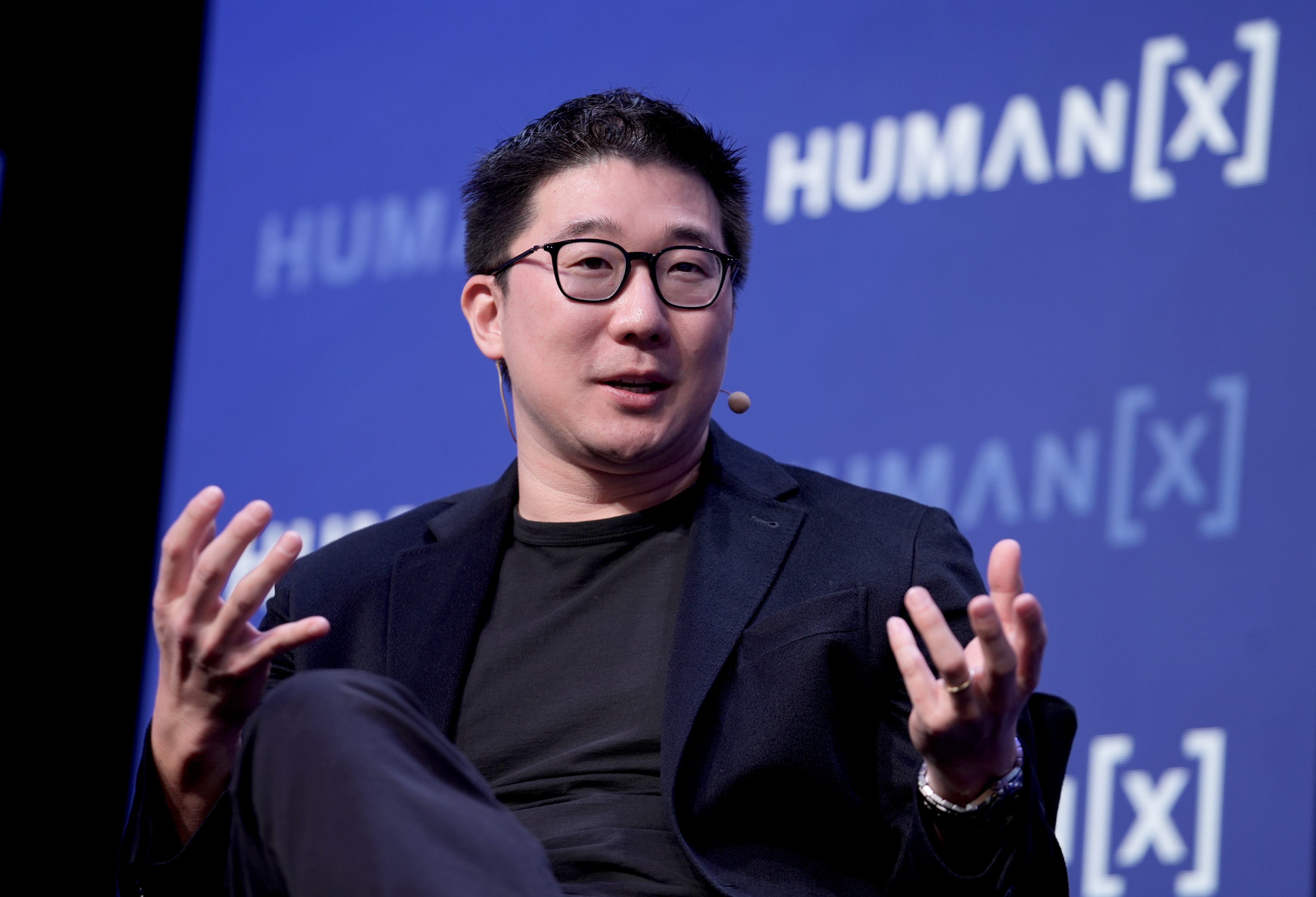 Airtable CEO Howie Liu is speaking while gesturing with his hands at a conference in Las Vegas.
