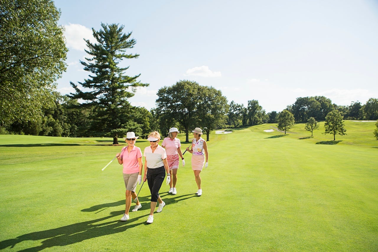 Older women walking and talking on a golf course.