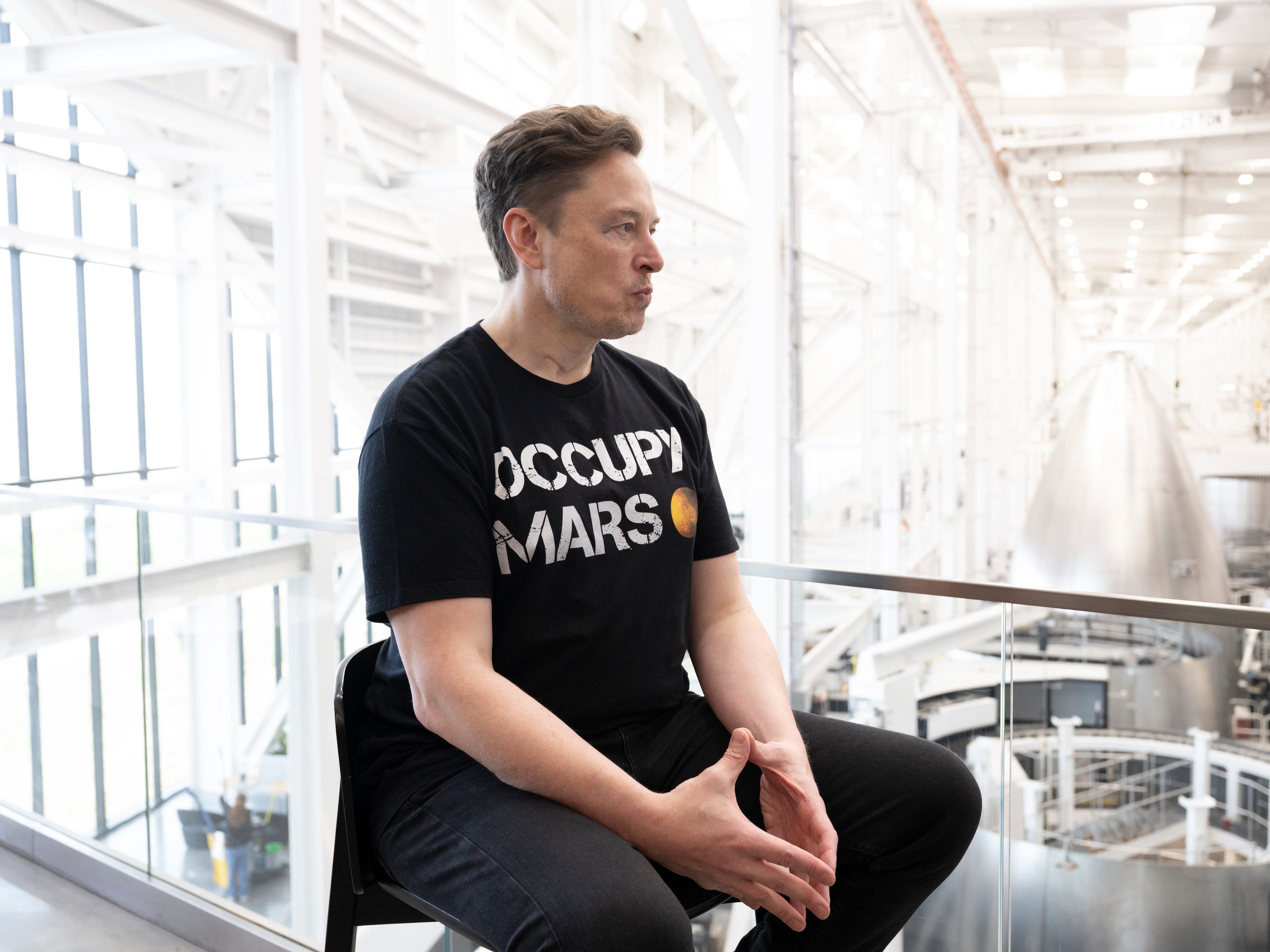 Elon Musk sitting in a chair.