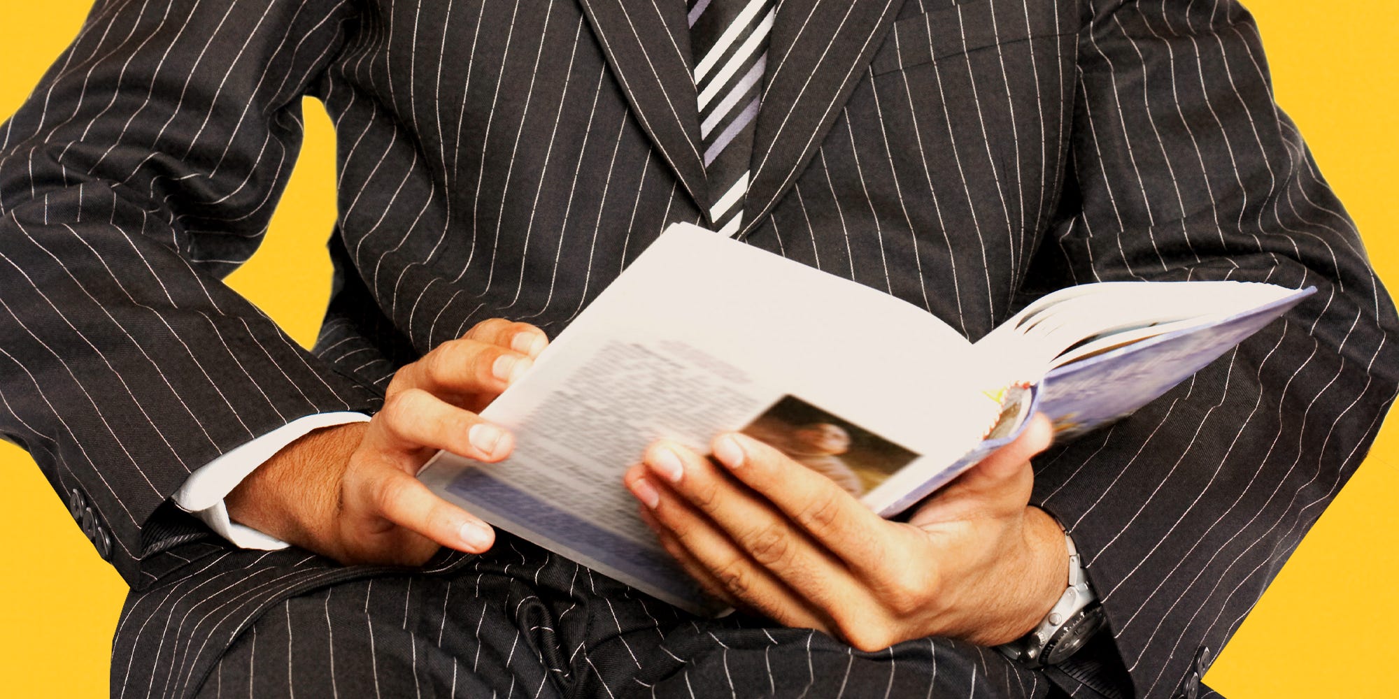 Man in striped suit reading a non-fiction book.