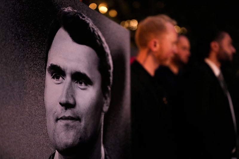 A photo of a black and white poster showing Charlie Kirk in the foreground at a vigil for Charlie Kirk