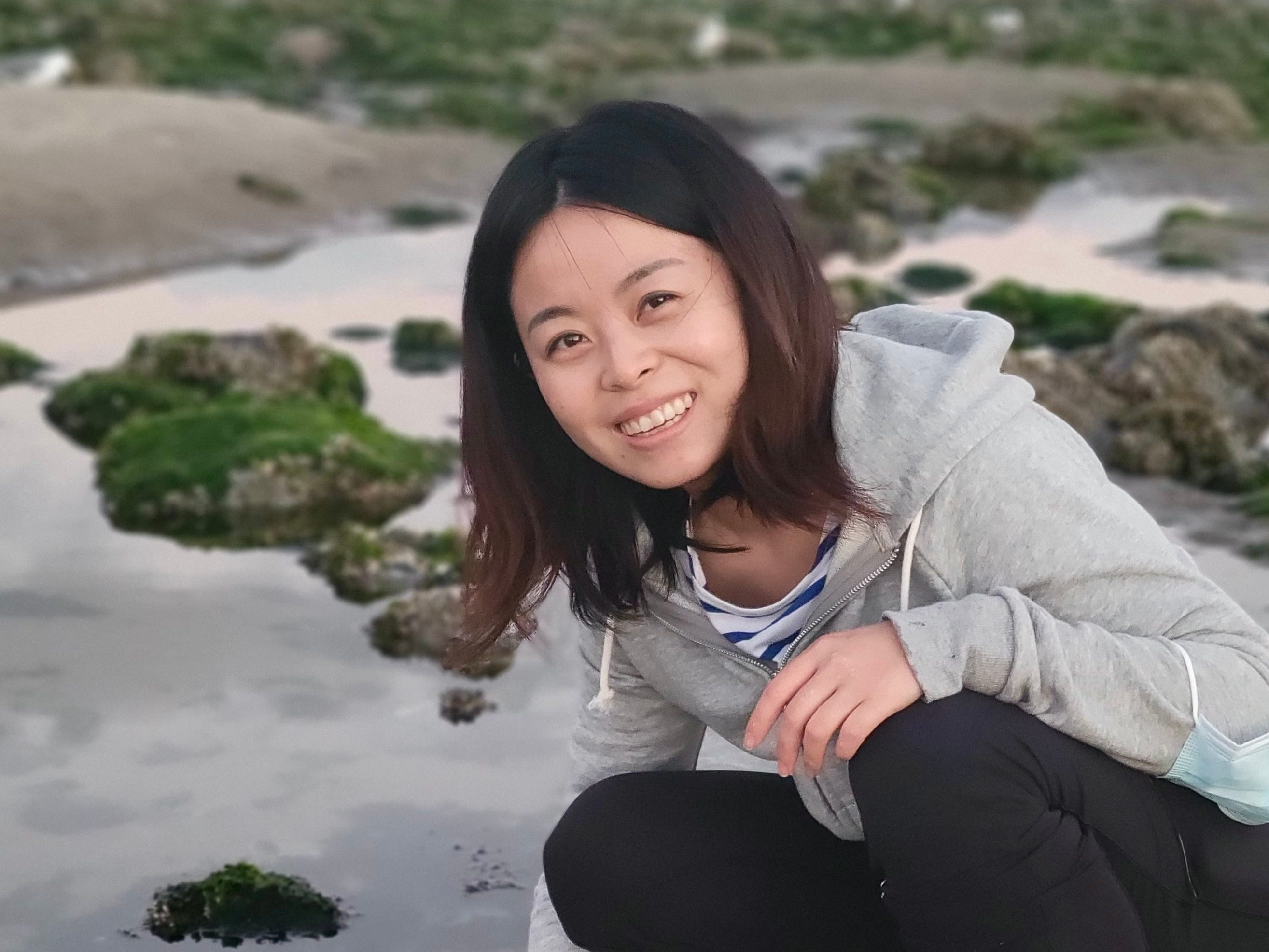 Amy Ma holding a crab in a pool of water.