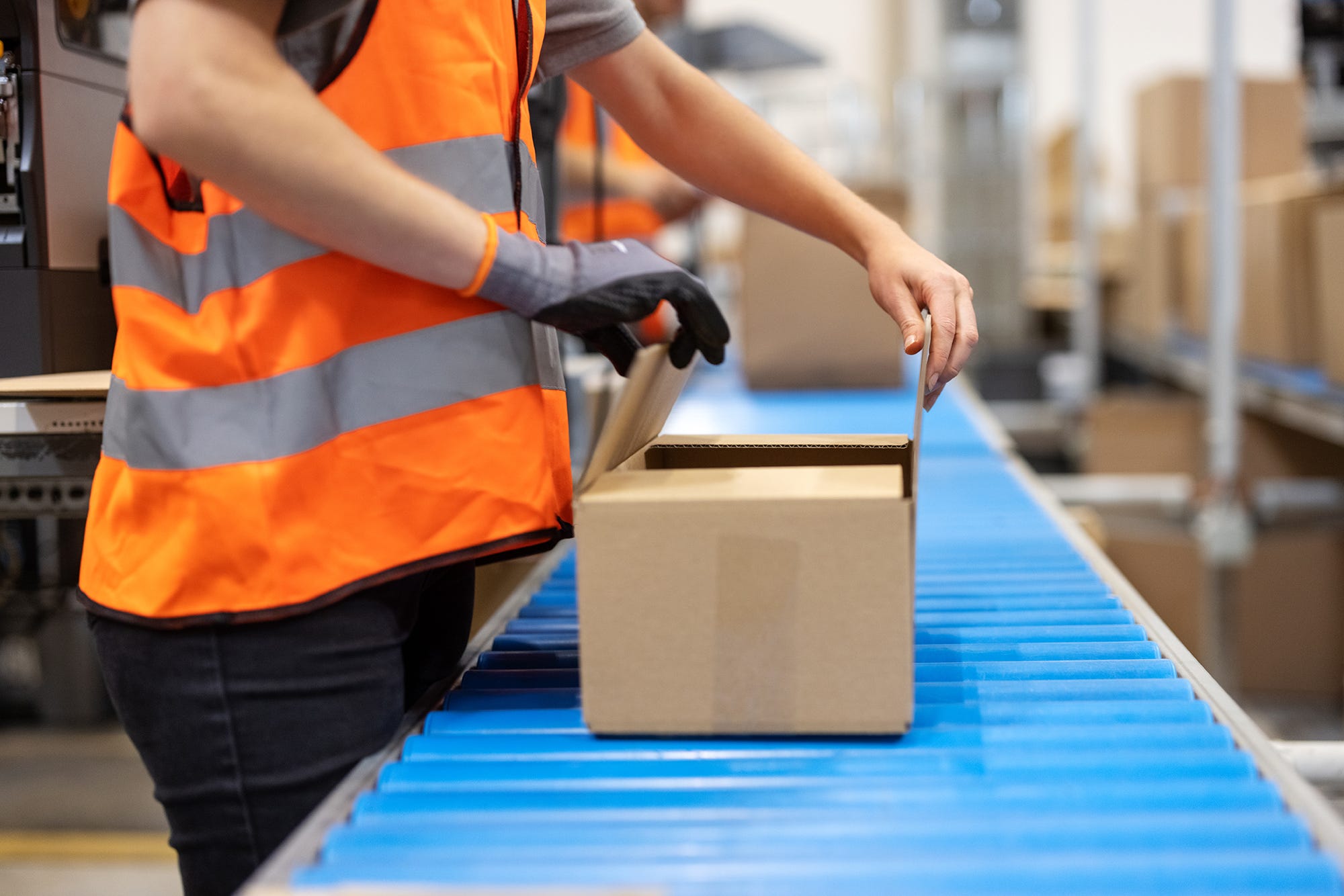 Person boxing package on conveyor belt