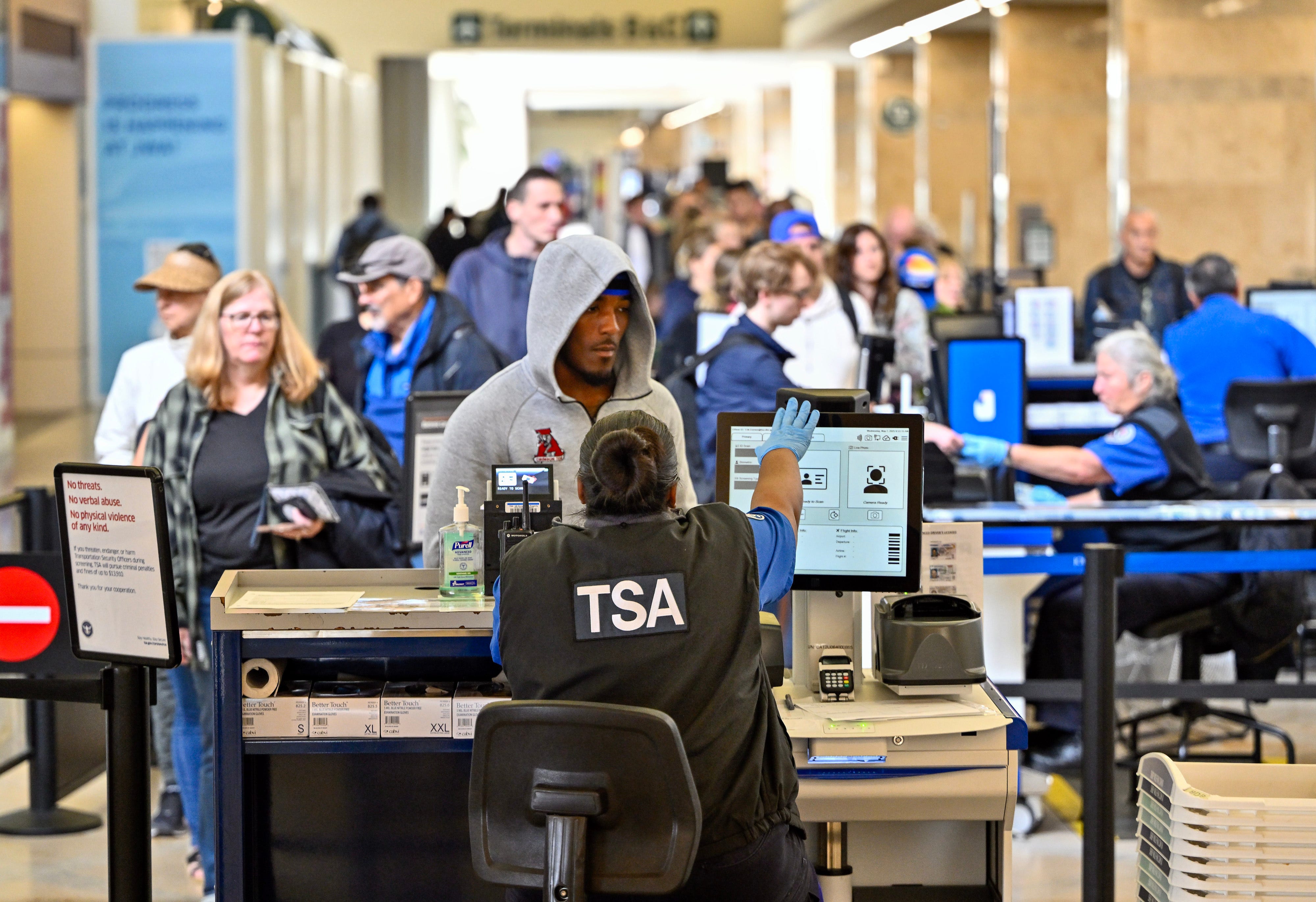 Passenger in a grey hoodie waits at a TSA line.