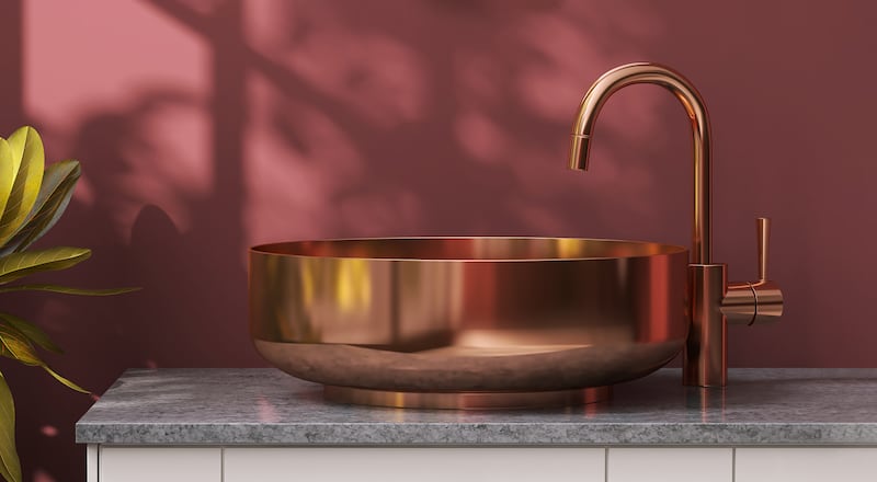 Modern marble bathroom vanity counter top with brass round washbasin in front of burgundy painted wall