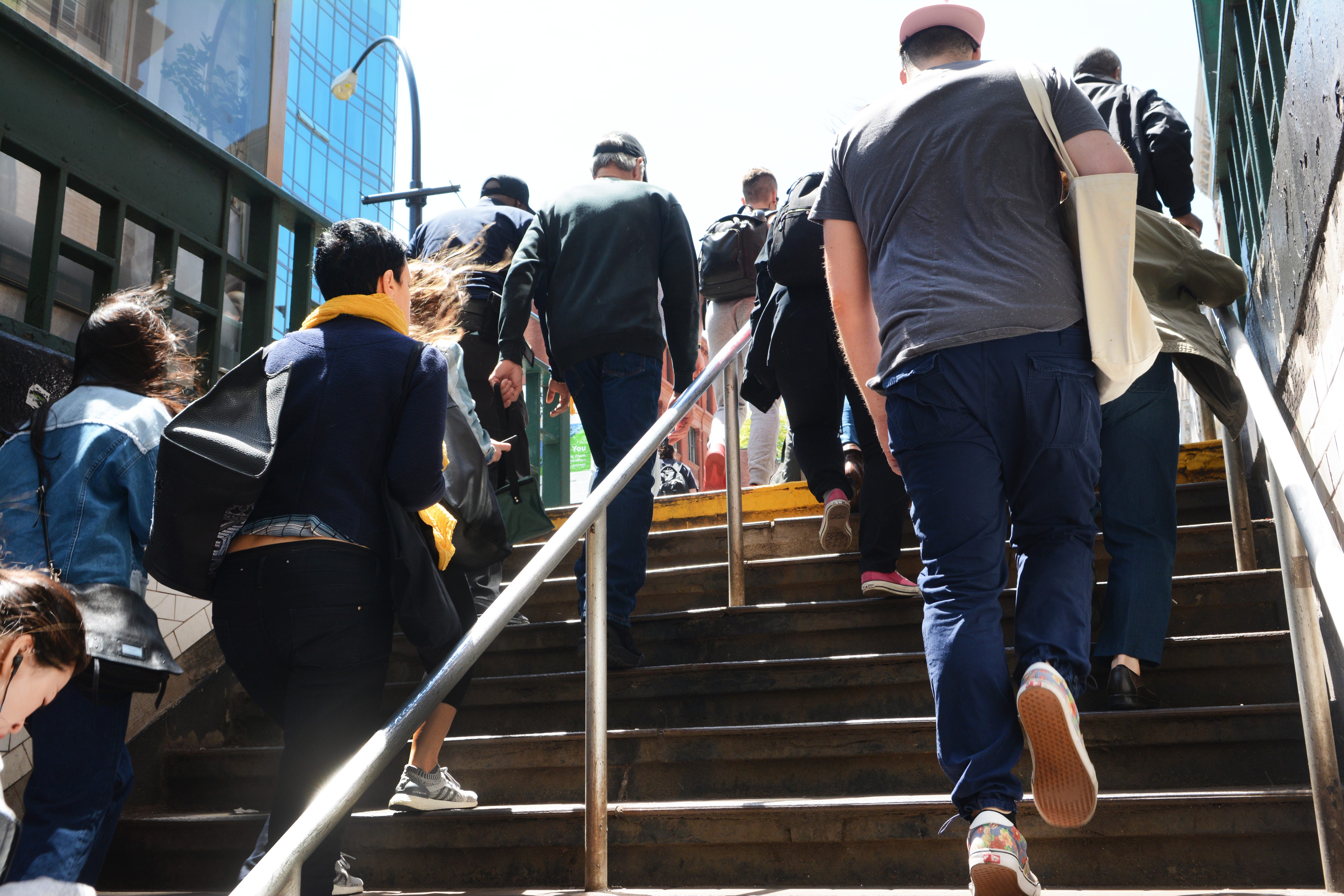 People walk up the stairs and out of the subway