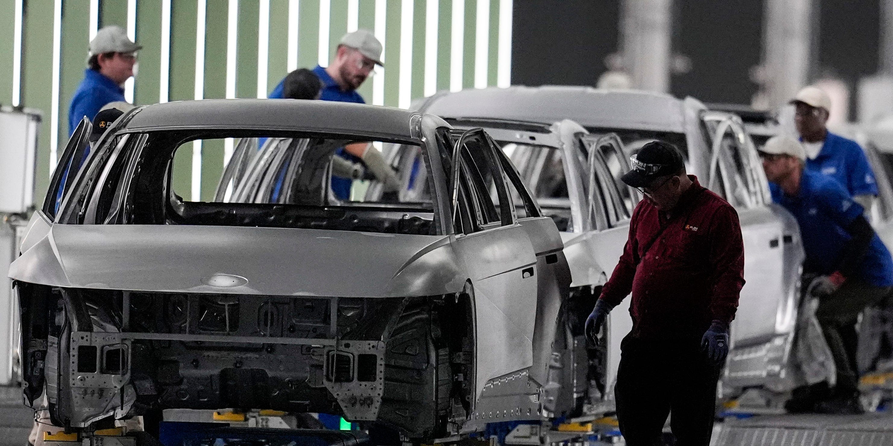 Employees work the line of a car manufactory.