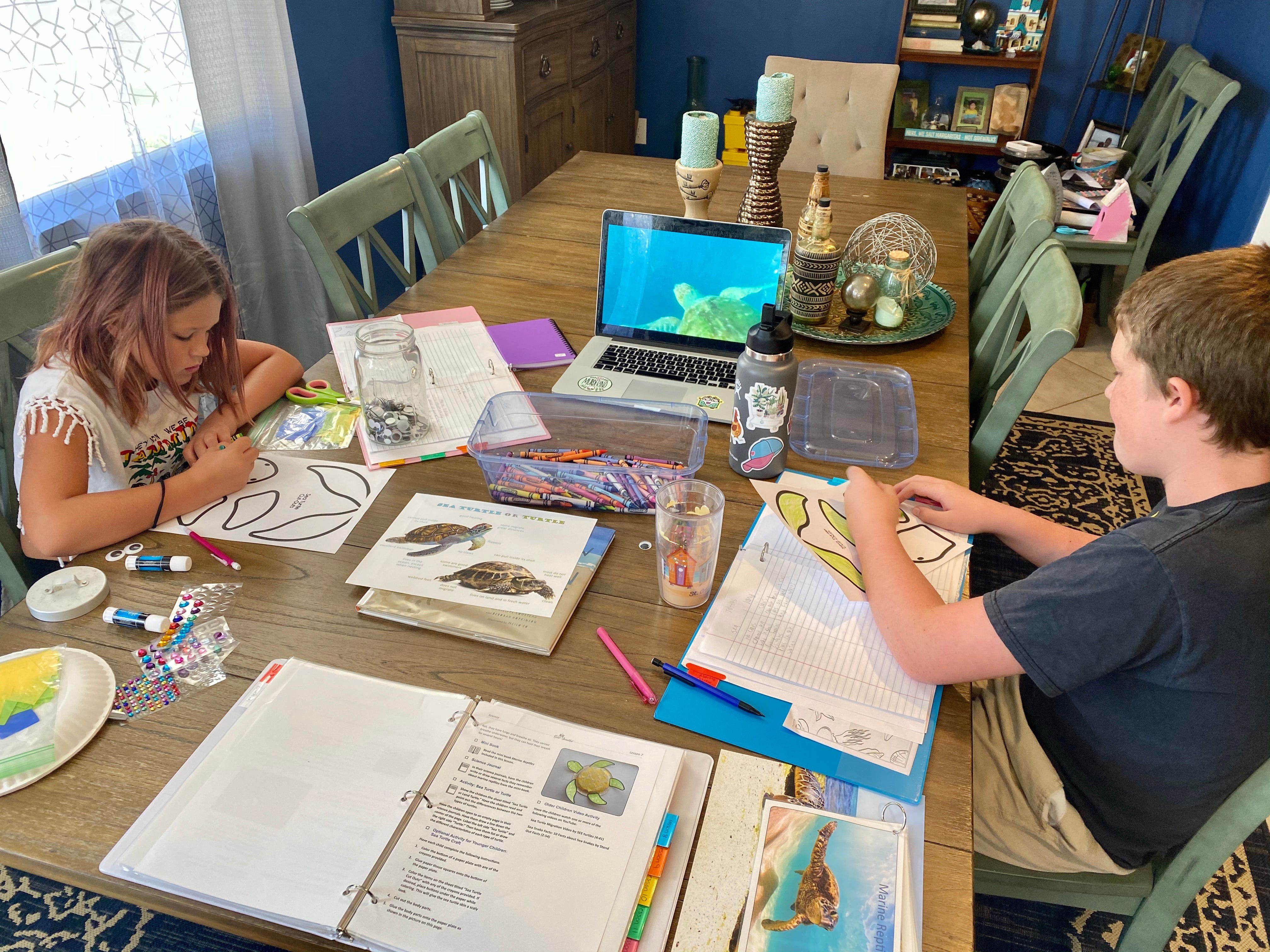 The author's two kids while being homeschooled at their dining room table.