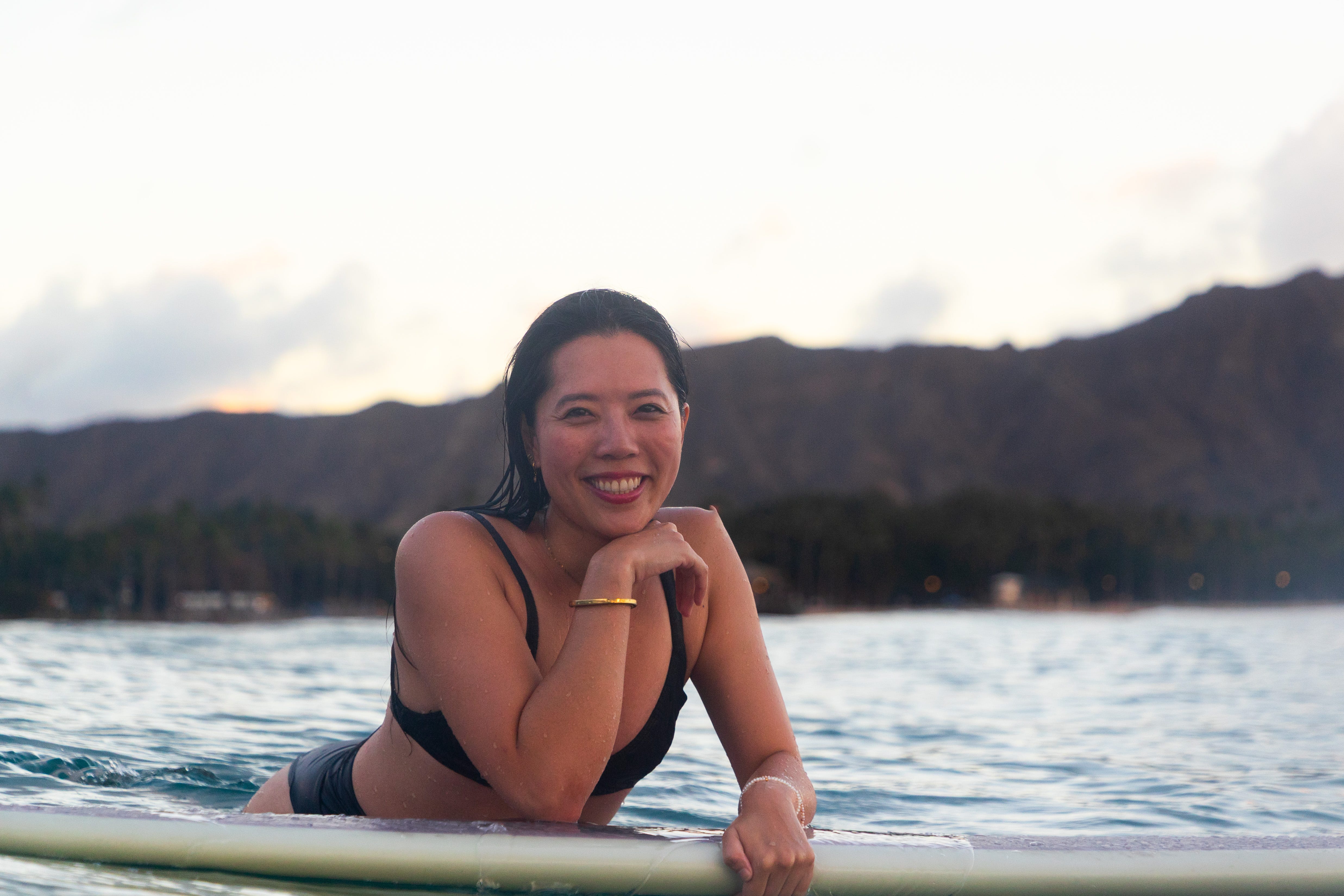 Jessica Yen smiles as she rests on a surfboard