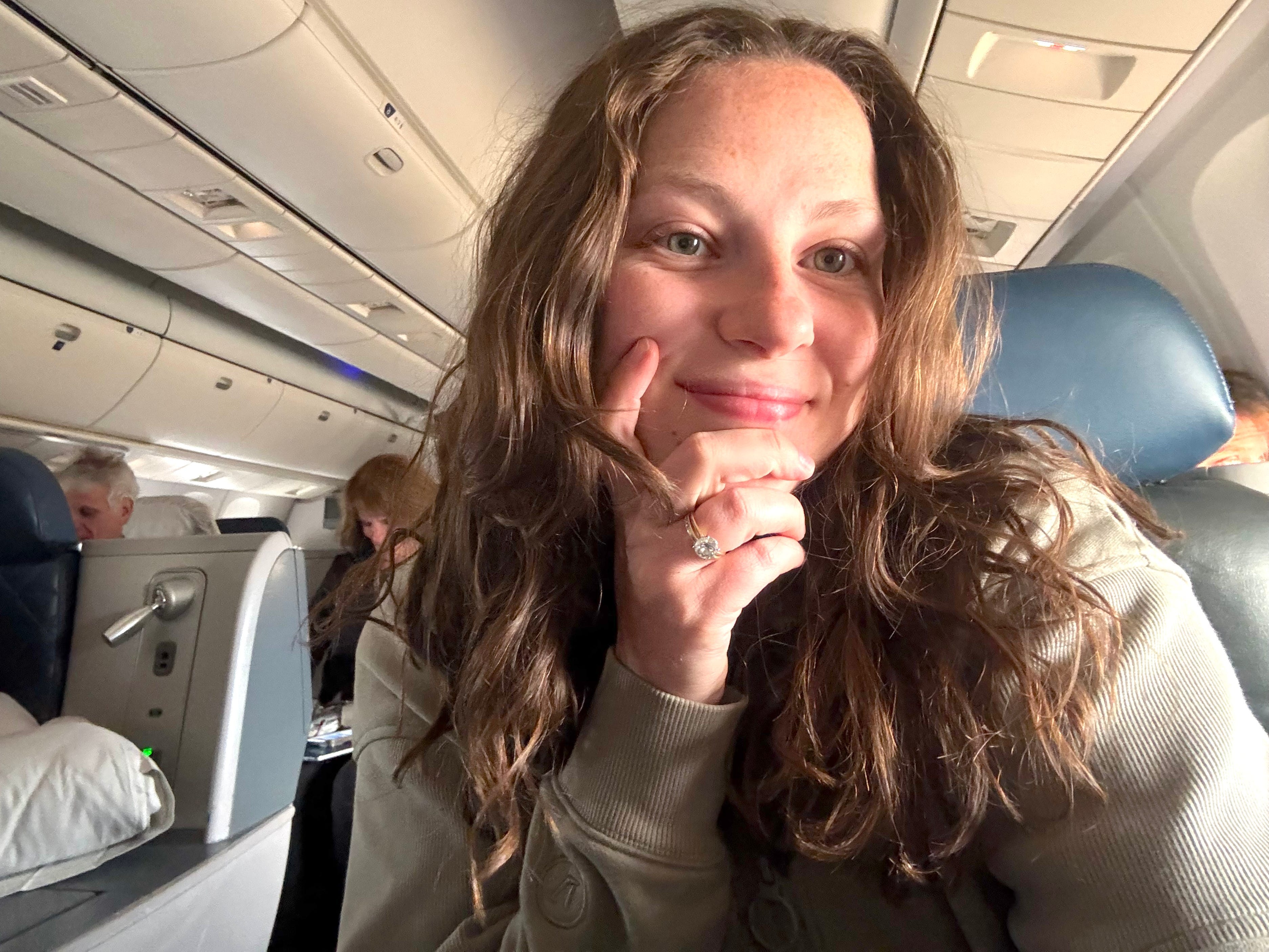 A selfie of a woman sitting in a business class seat on a Delta plane.