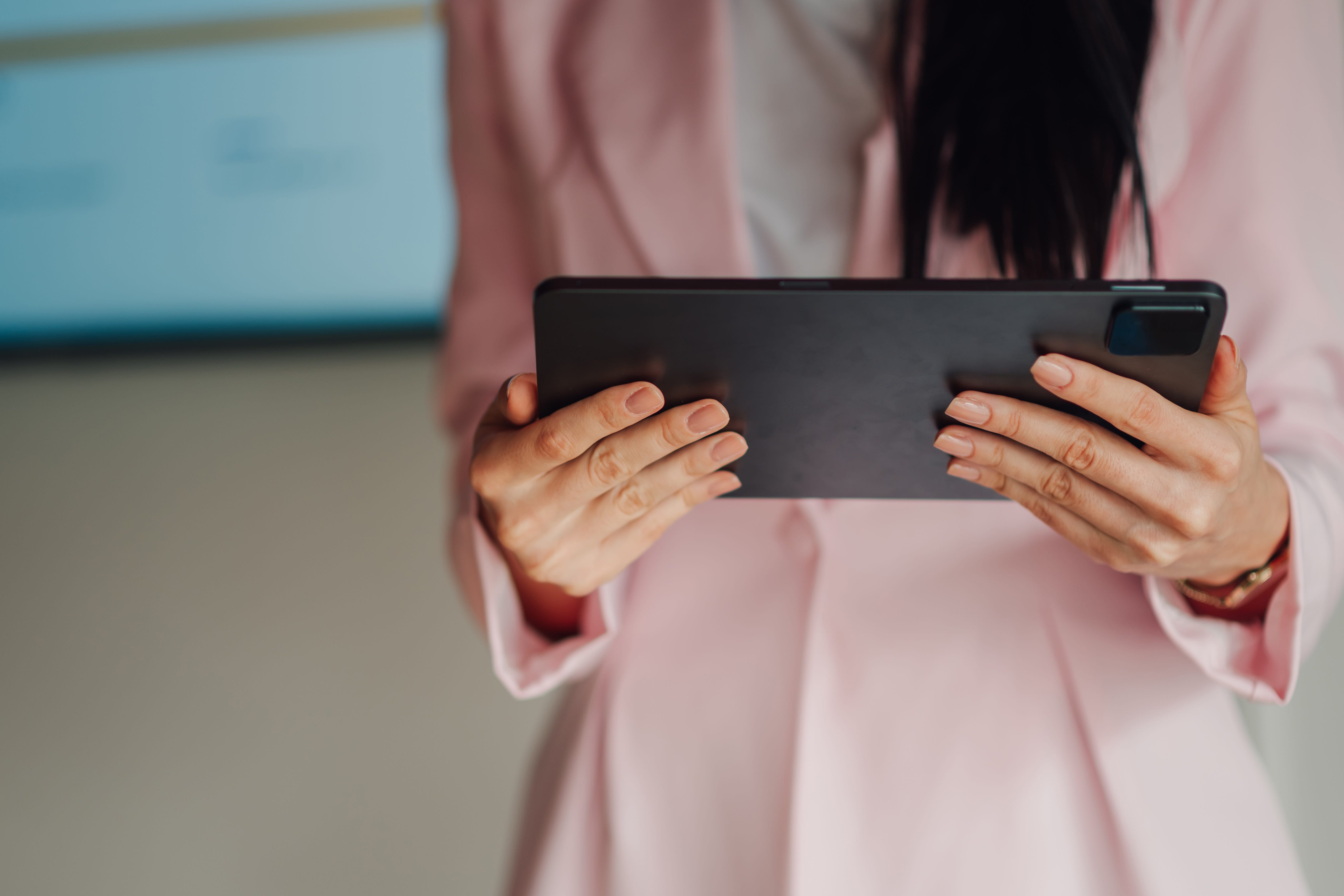 Businesswoman working in a modern office environment, using a digital tablet to browse information and communicate efficiently.