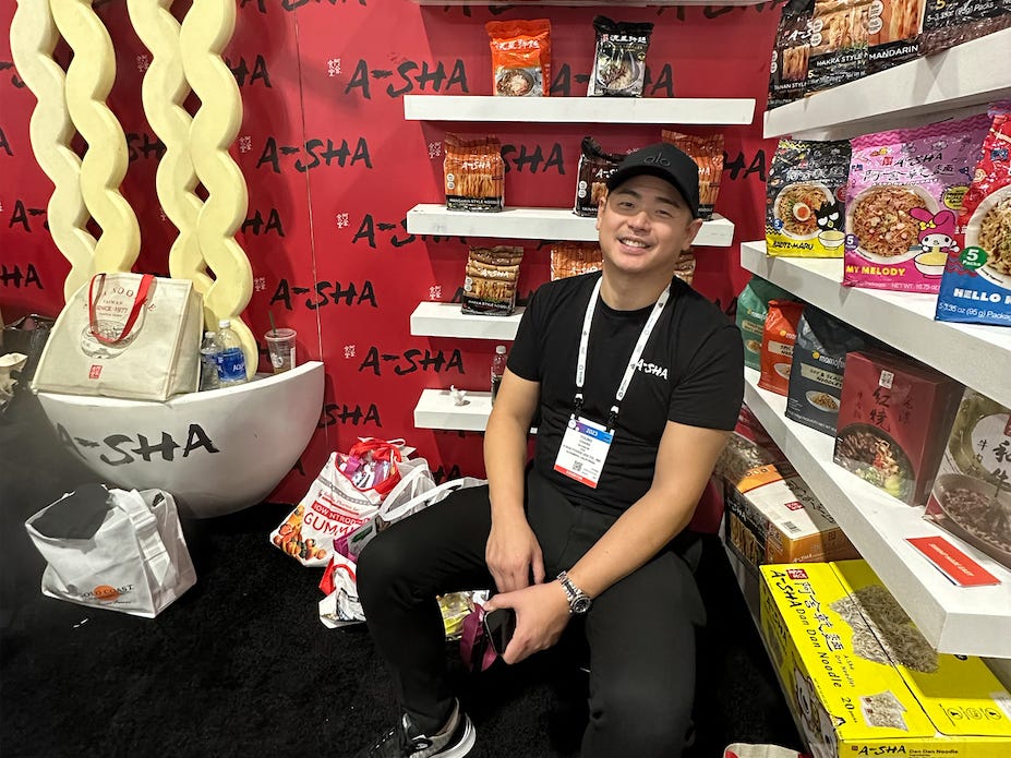 Young Chang, CEO of A-Sha Foods USA, poses next to a display of A-Sha products.