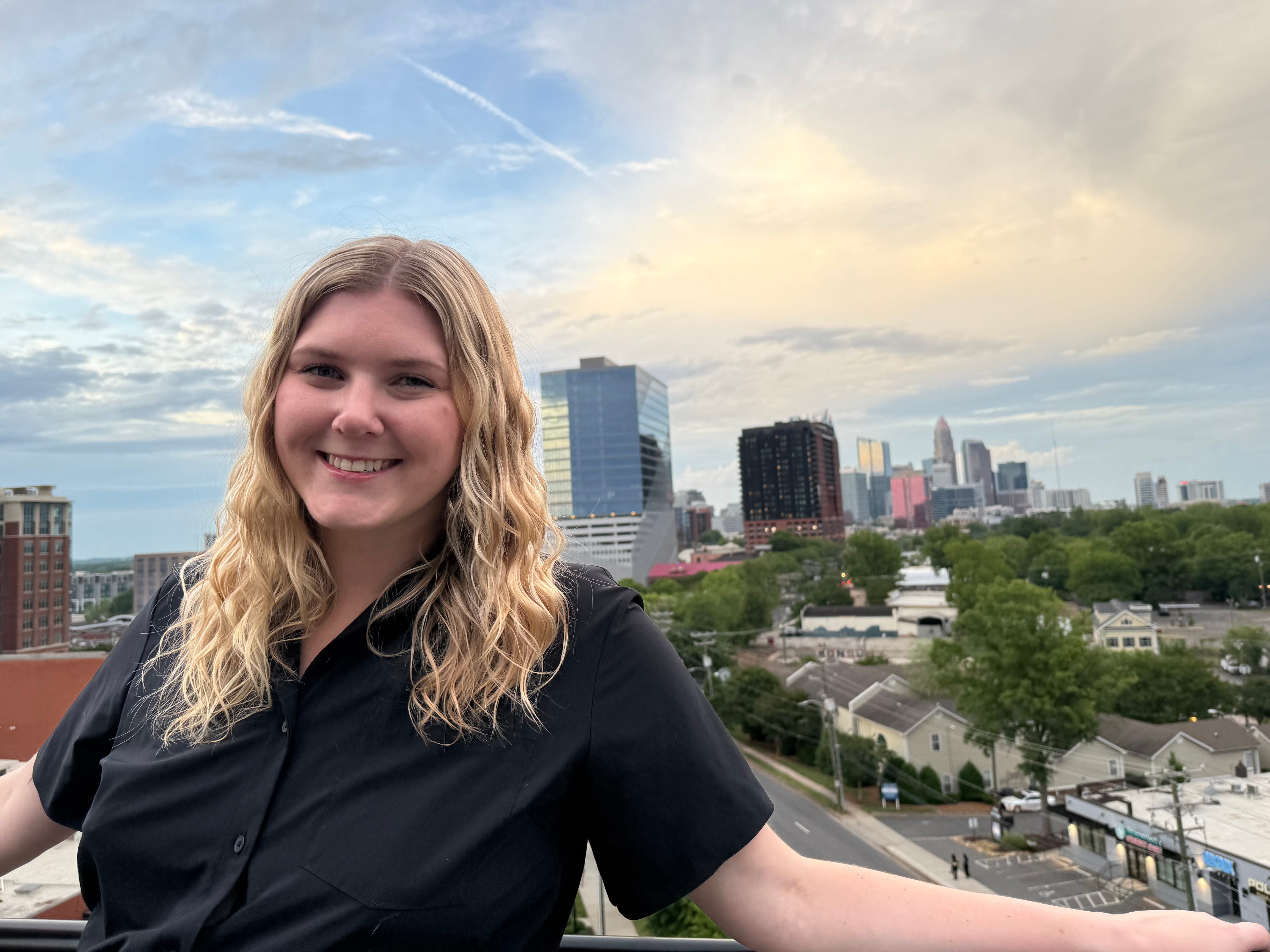Author Elizabeth Wright smiling in front of Uptown Skyline in Charlotte