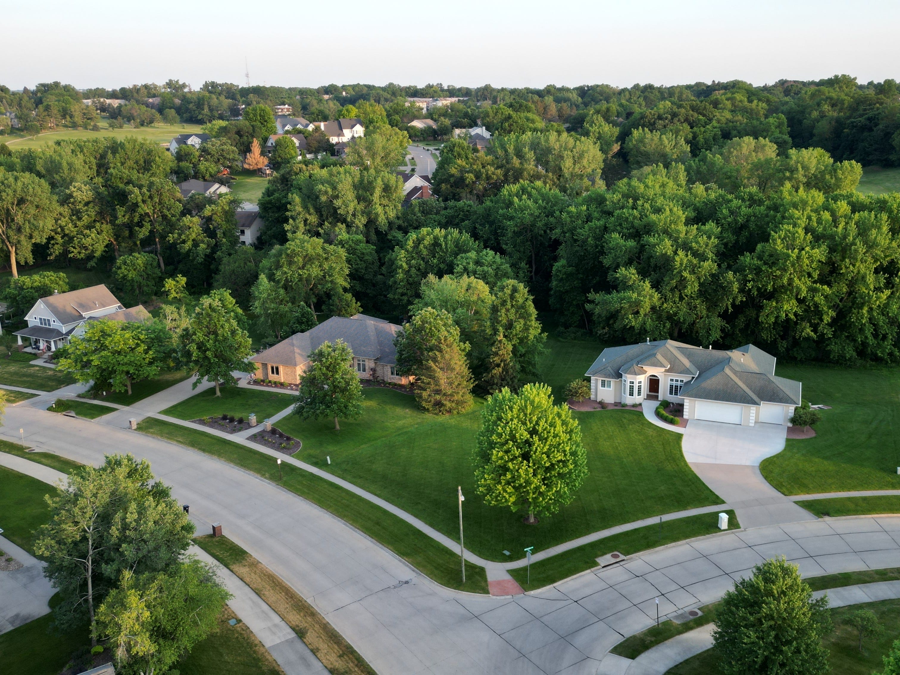 Aerial view of suburb in Iowa with many trees, spaced-out houses