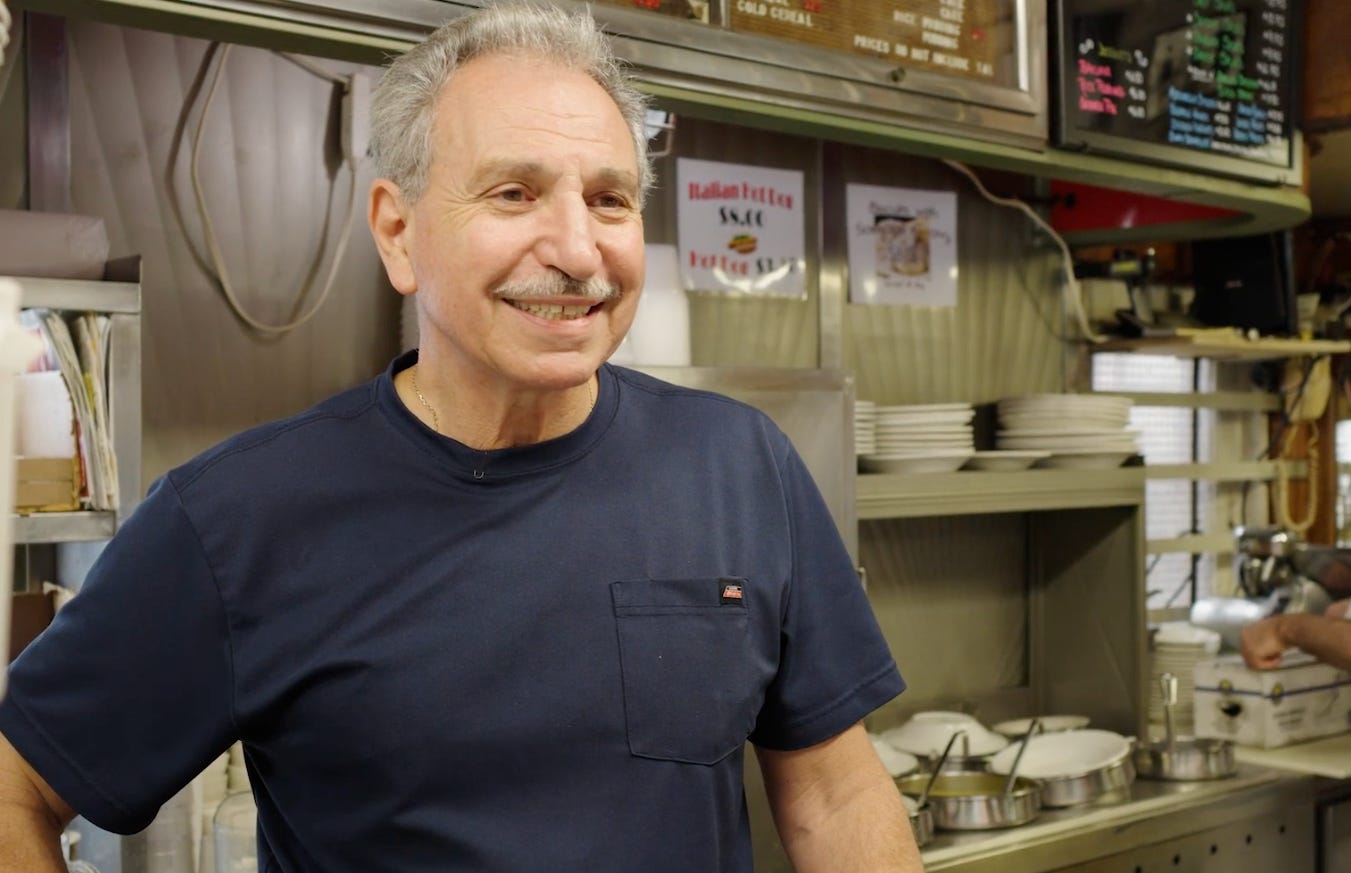 man in blue t-shirt standing inside of Summit Diner behind counter