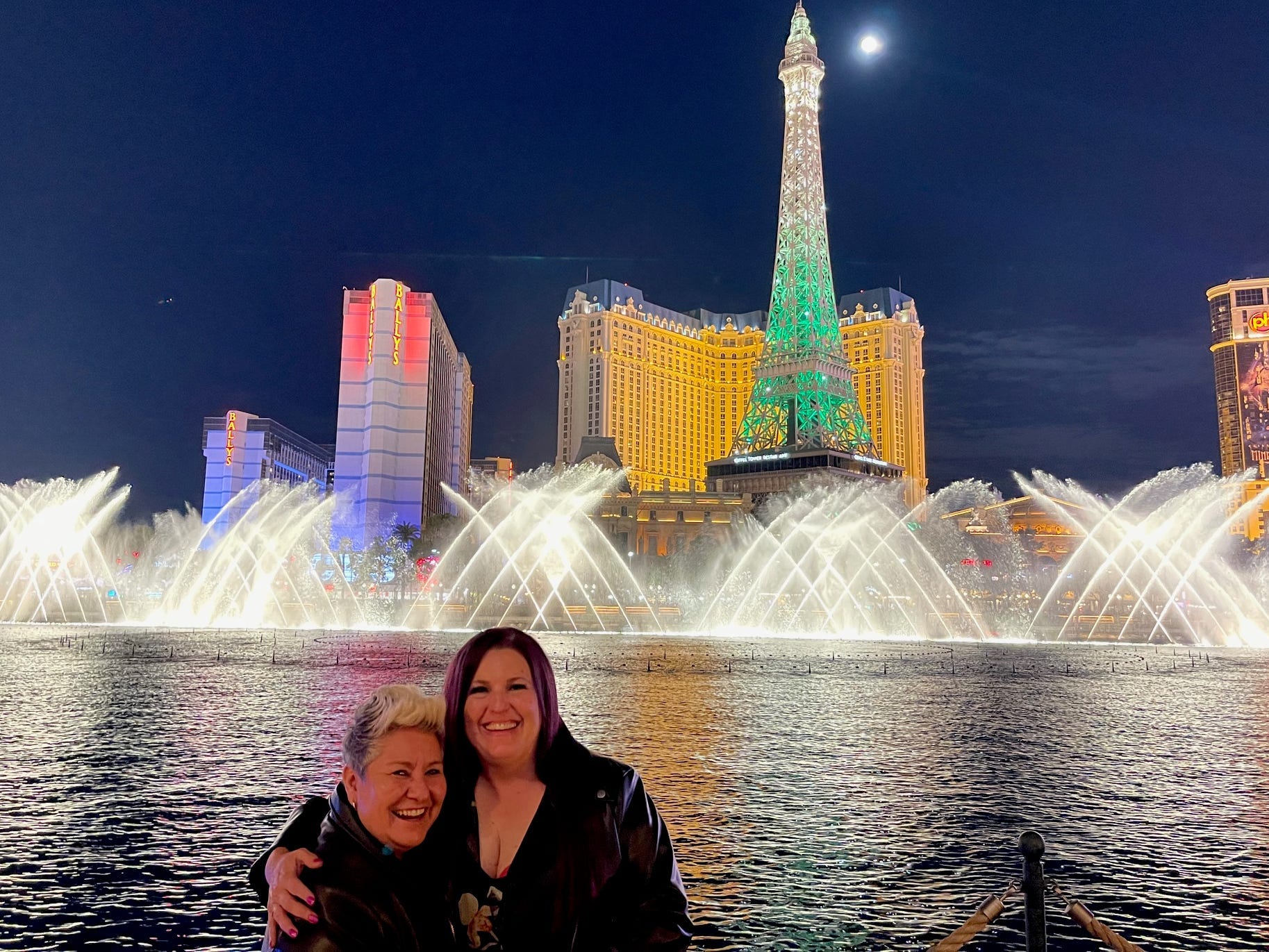 Author Danuelle Bauter smiling with person in front of lit-up Bellagio Fountains