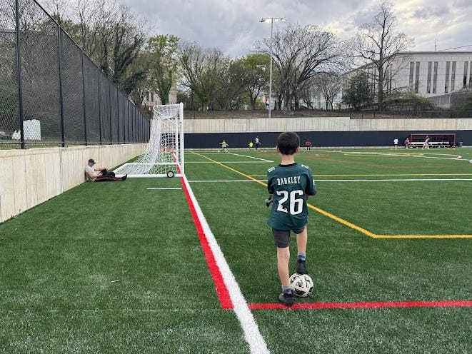 The author's son is wearing a soccer uniform and standing on a soccer field.
