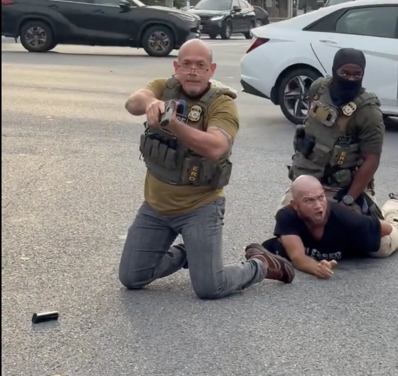 An ICE agent briefly pointed his pistol in the direction of onlookers on Wednesday. Some online noted that his magazine, seen in the bottom left of this screenshot, had fallen out of the weapon.