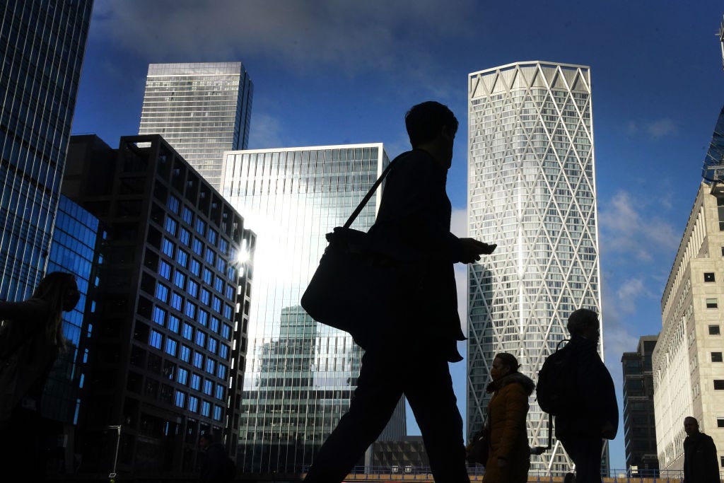 Office workers and commuters walk through Canary Wharf in London during the morning rush hour.