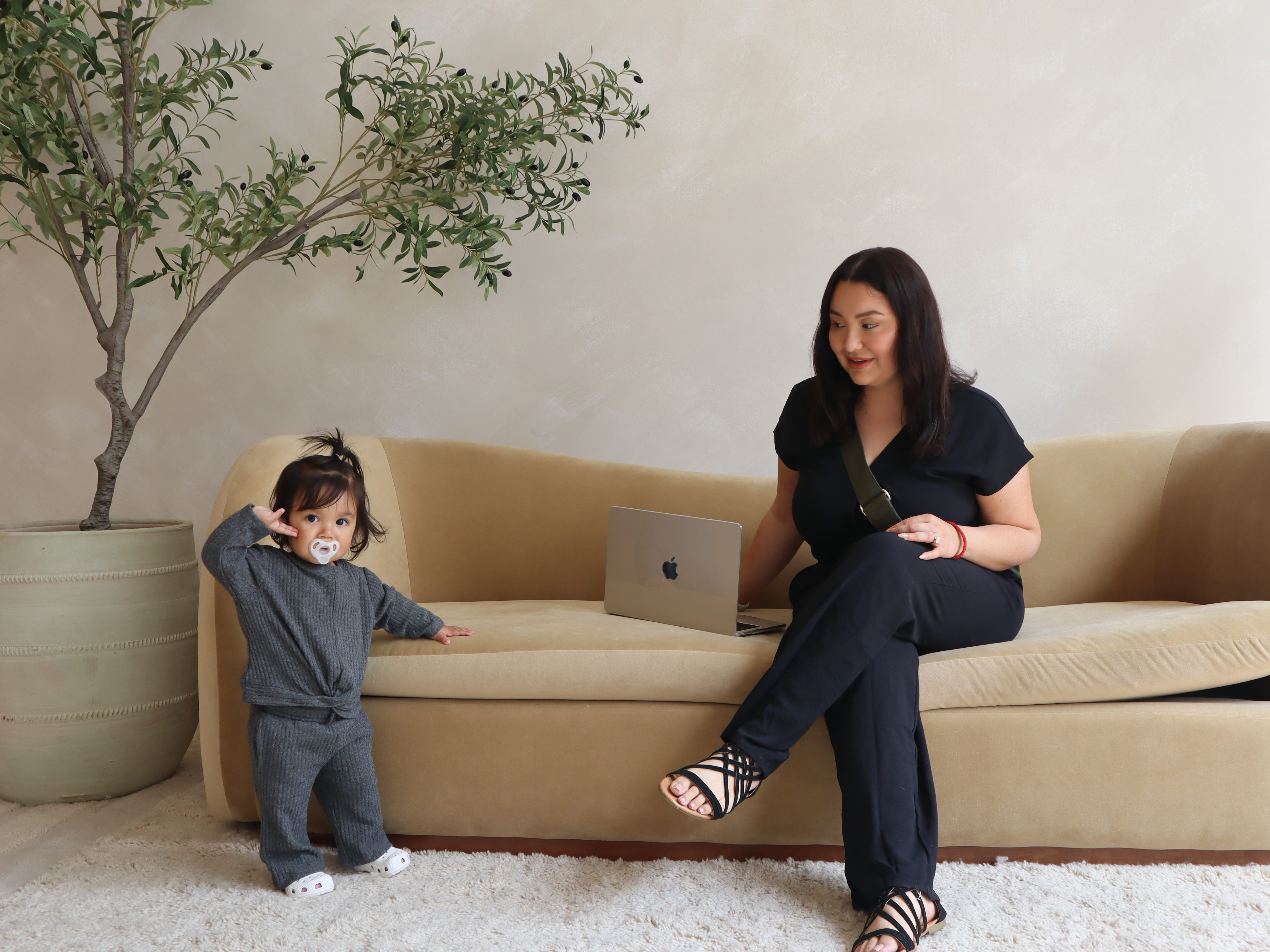 The author sitting on a couch with her daughter standing on the ground next to her.