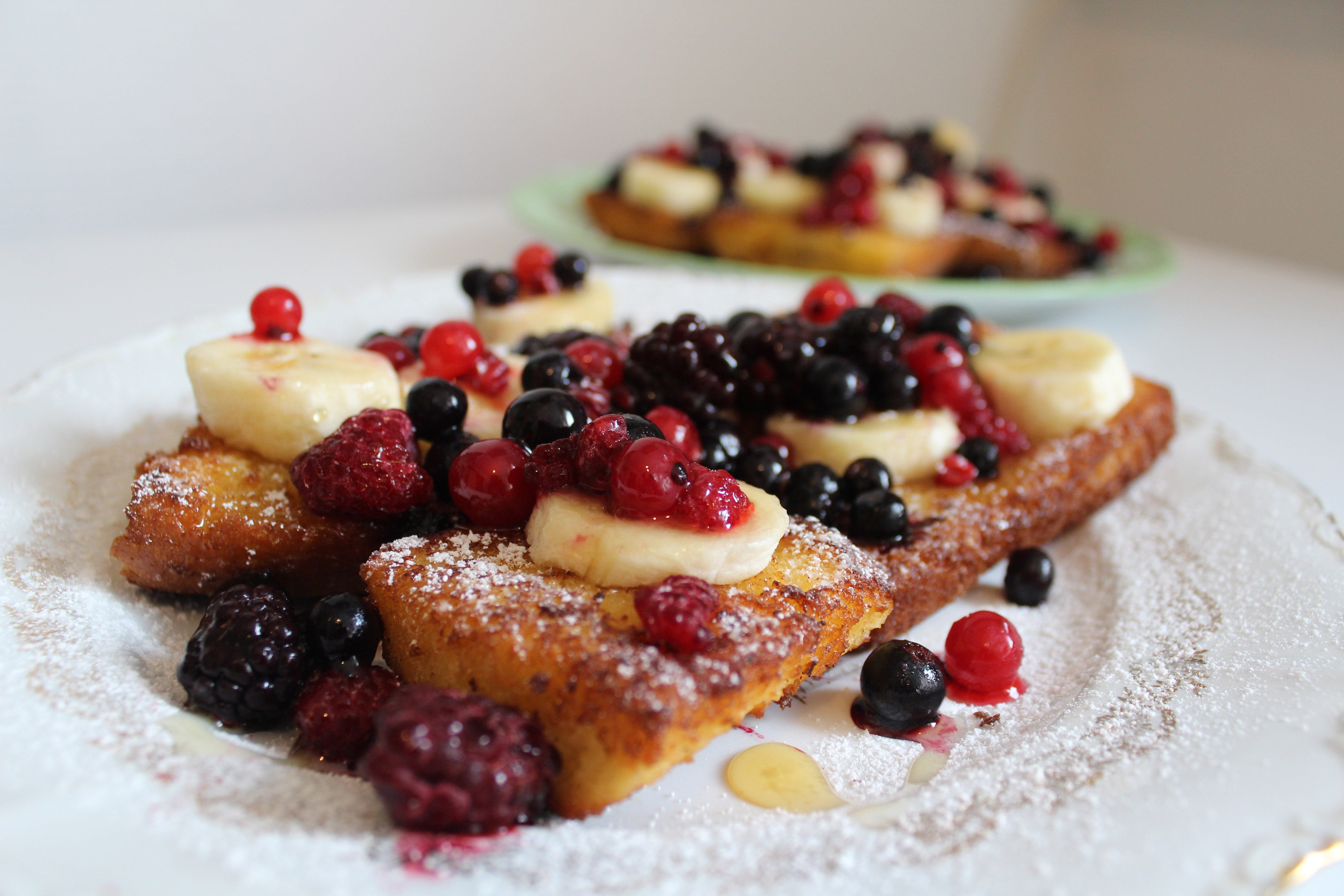french toast topped with berries, banana slices