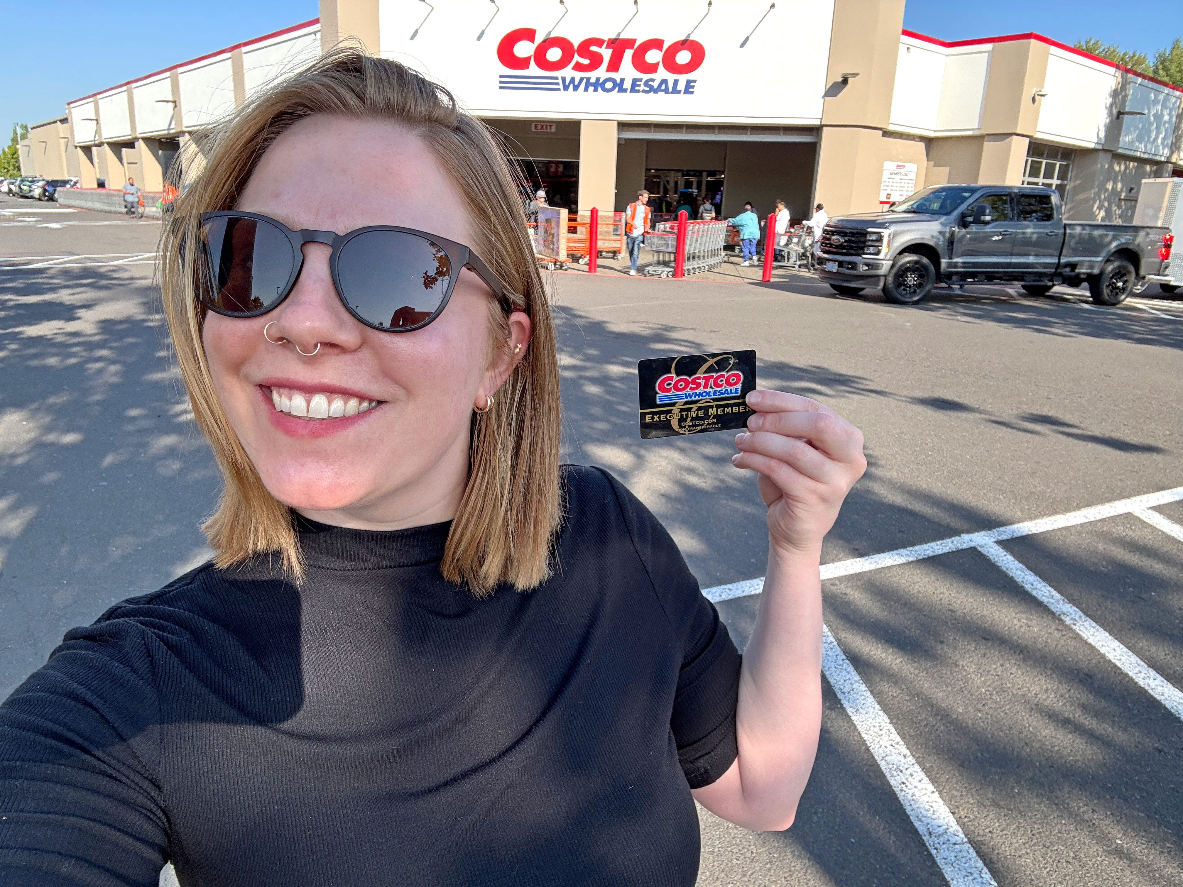 Gabrielle holds up a Costco executive member card in front of the store.