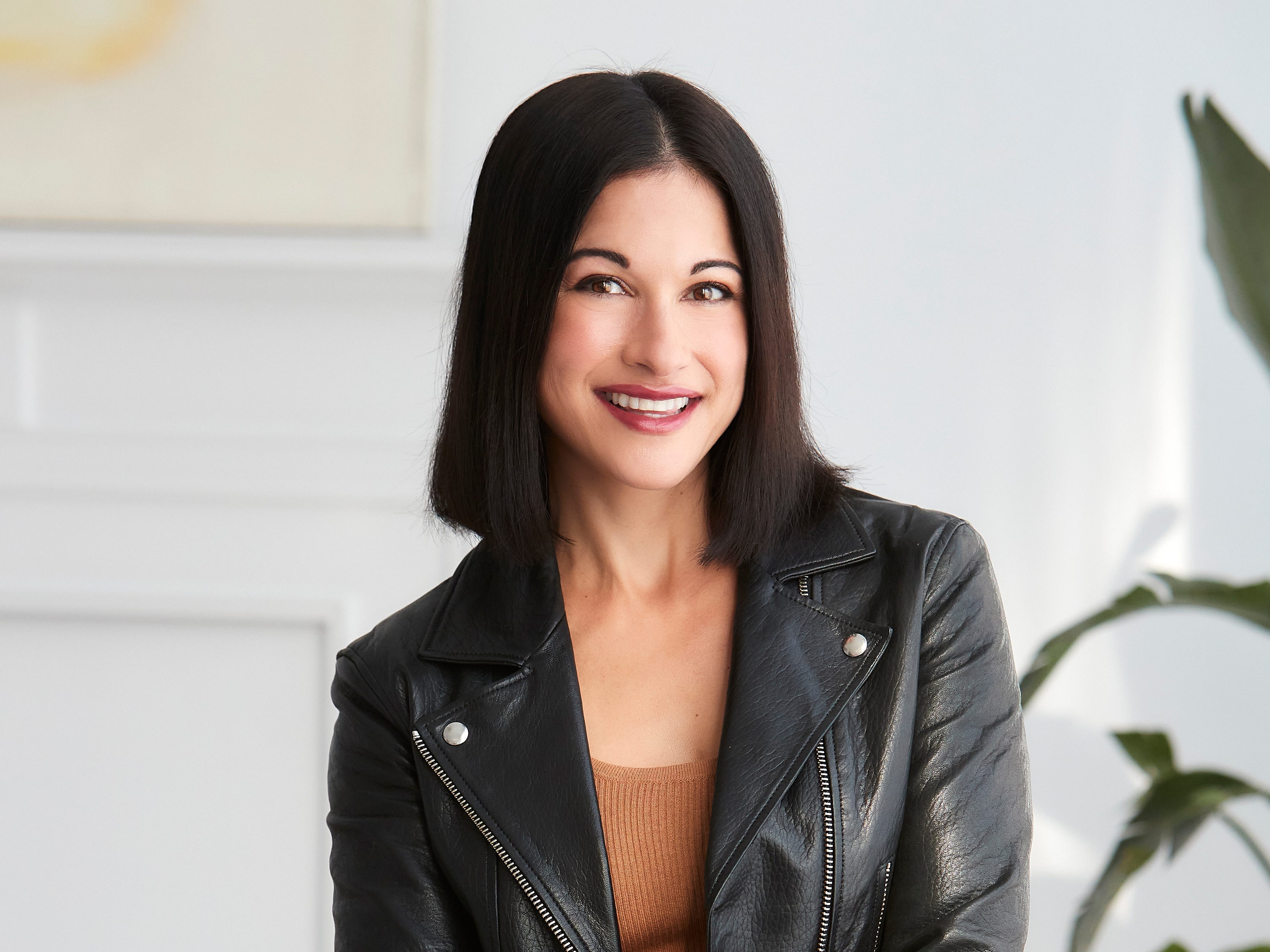 headshot of a woman in a brown dress and a leather jacket