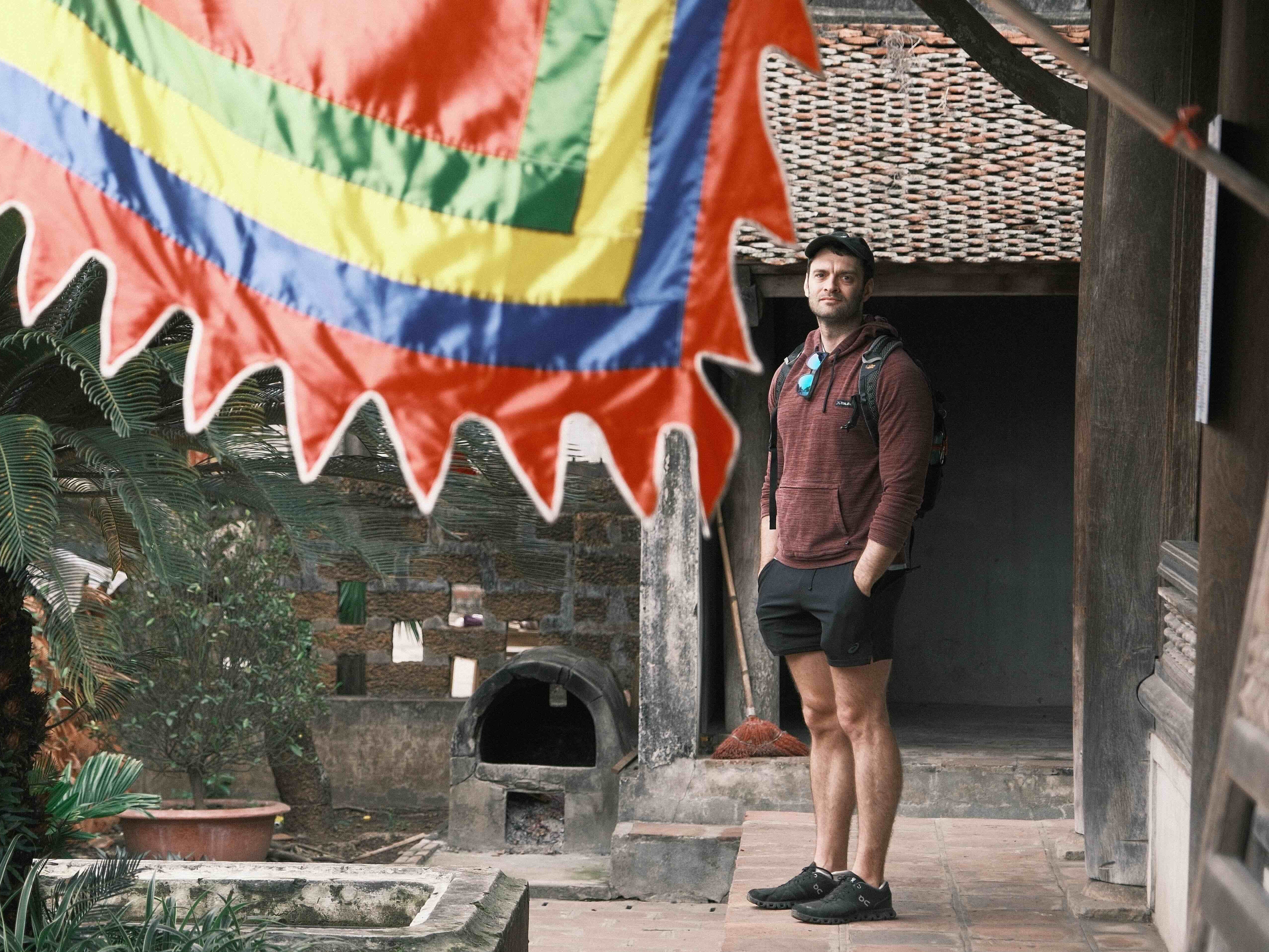 Joshua Zukas is standing near a flag in Vietnam.