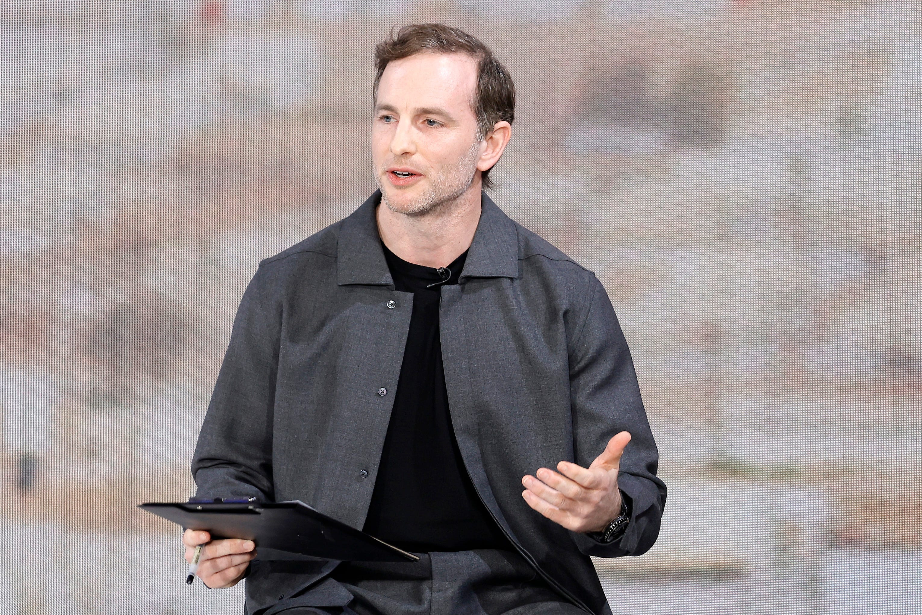 Joe Gebbia is holding a clipboard and gesturing with his left hand.
