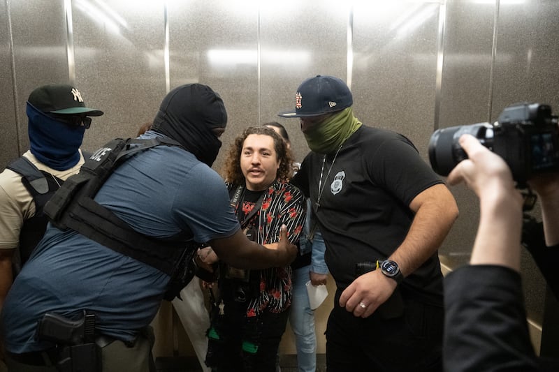 Federal agents throw Dean Moses, photographer for AM New York, out of the elevator while detaining an immigrant.