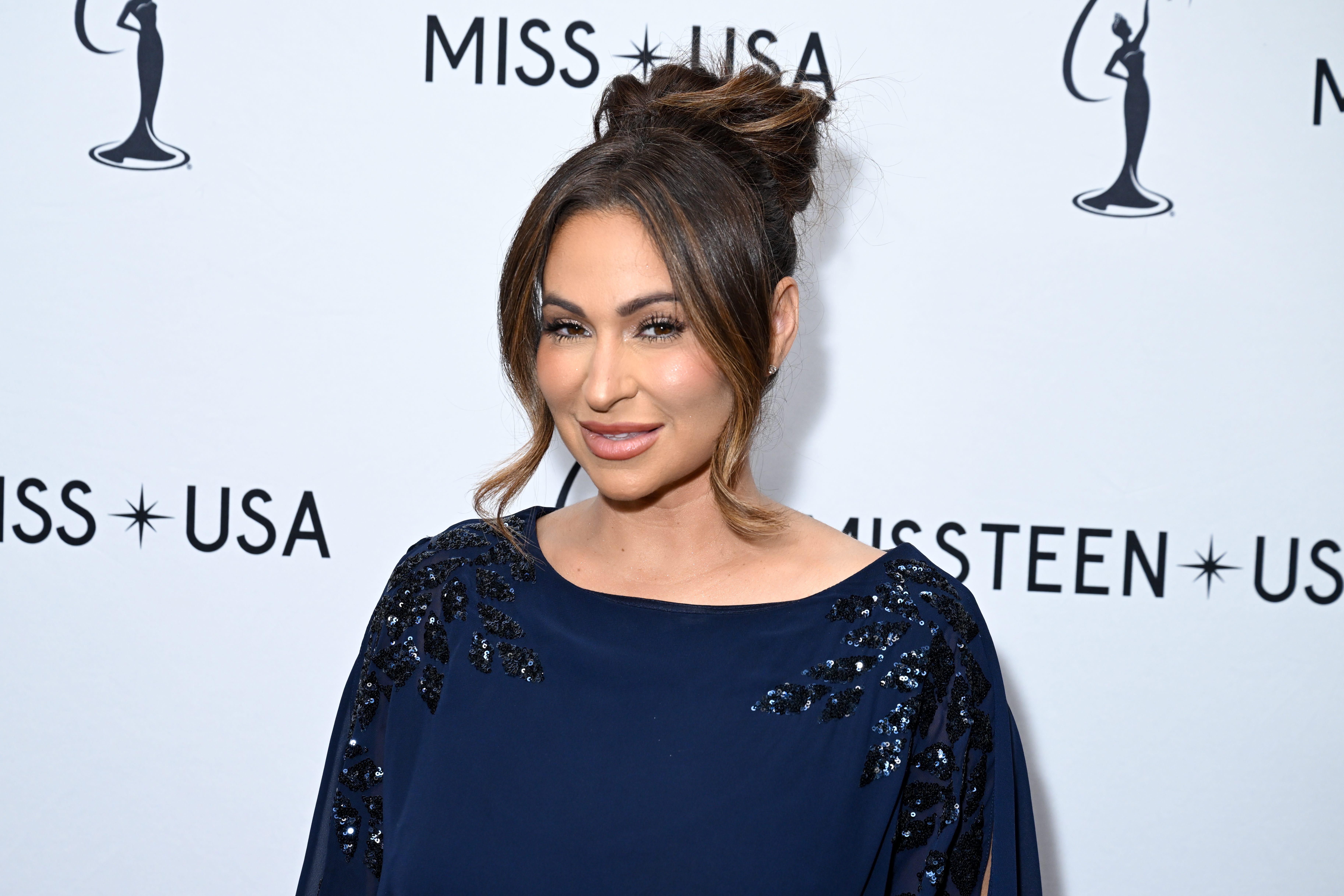 Miss USA CEO Laylah Rose in a blue dress on a step and repeat.