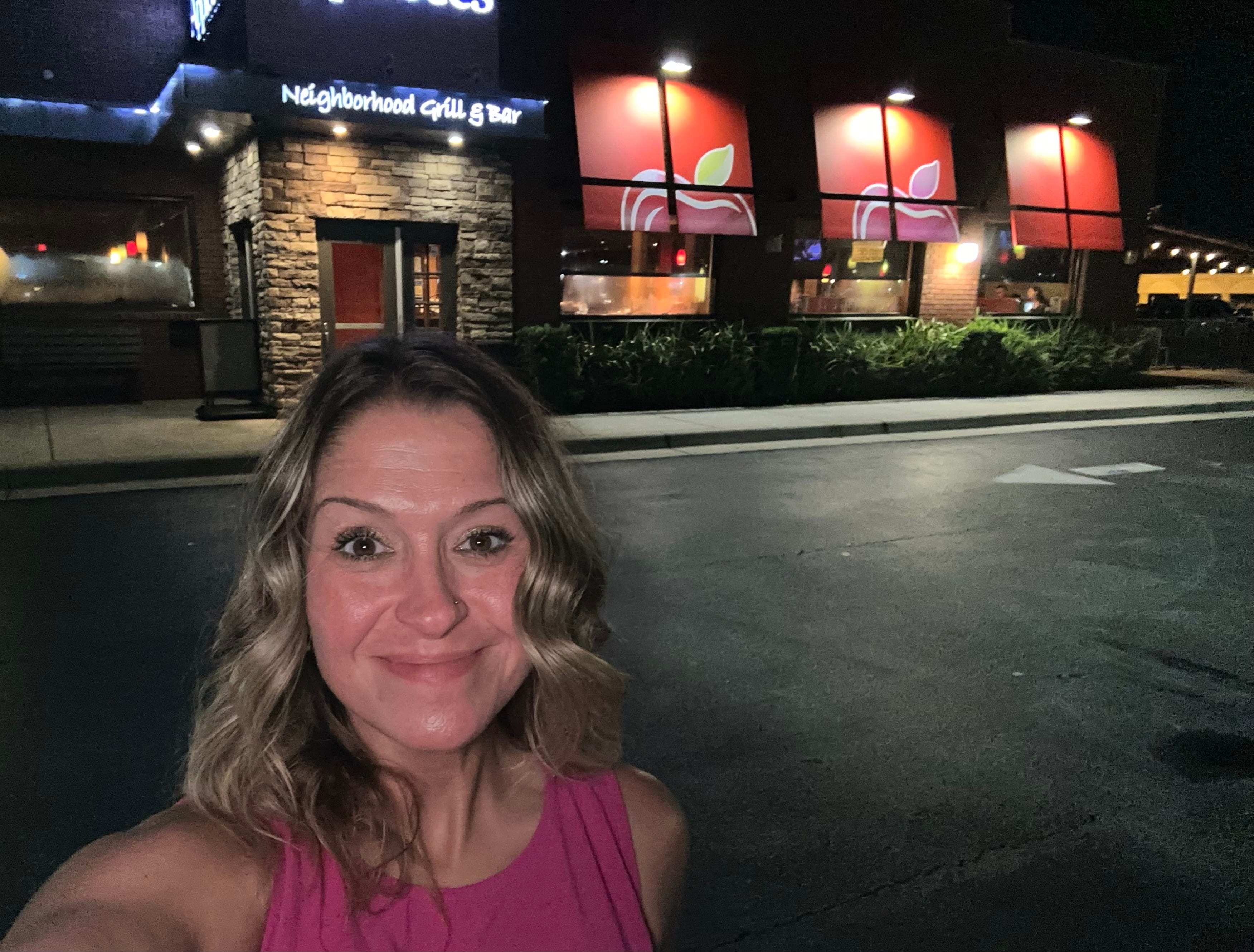 Author Terri Peters smiling in front of an Applebees at night