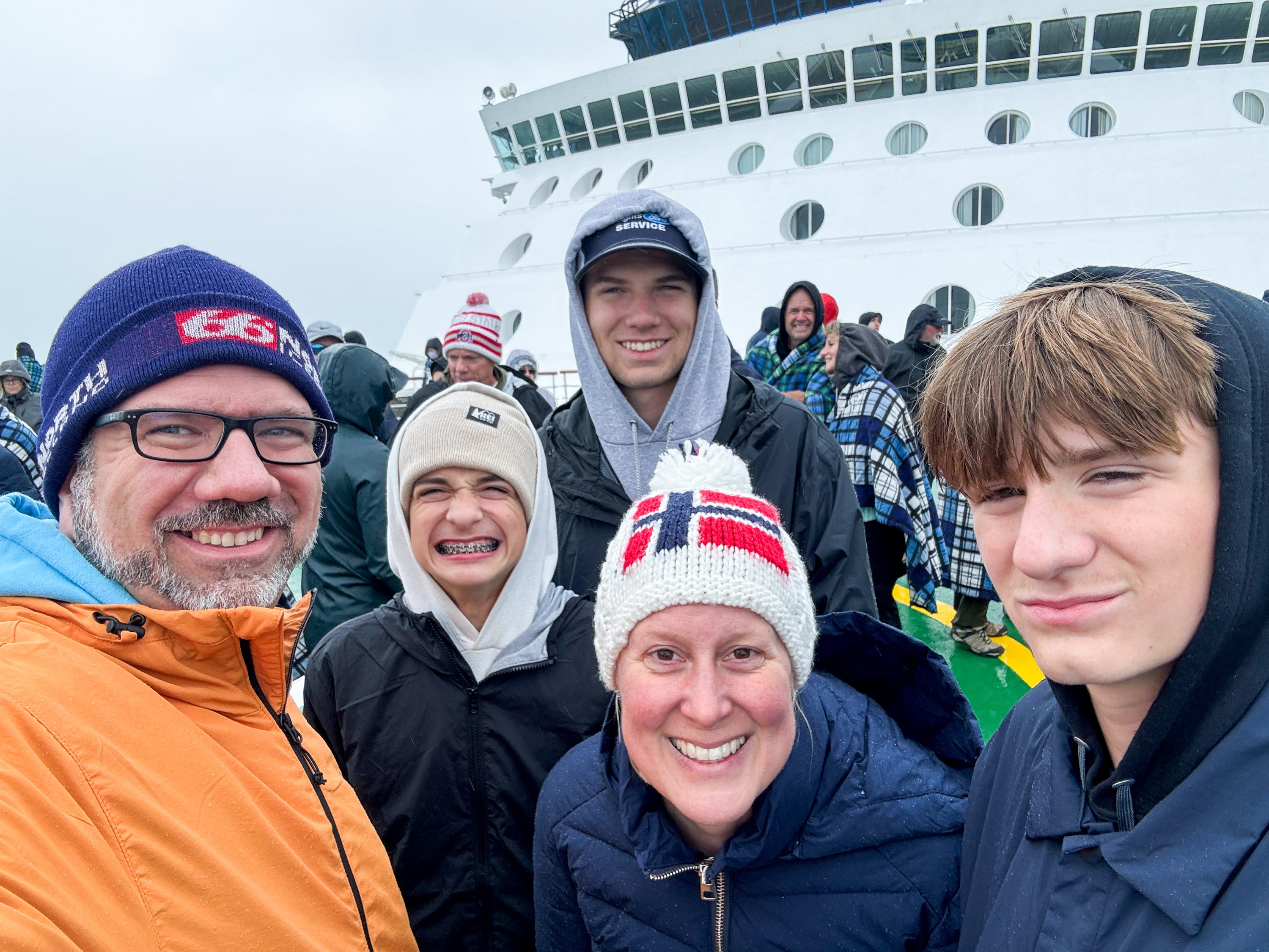 Chris, his wife, and three sons smile in front of a cruise ship.