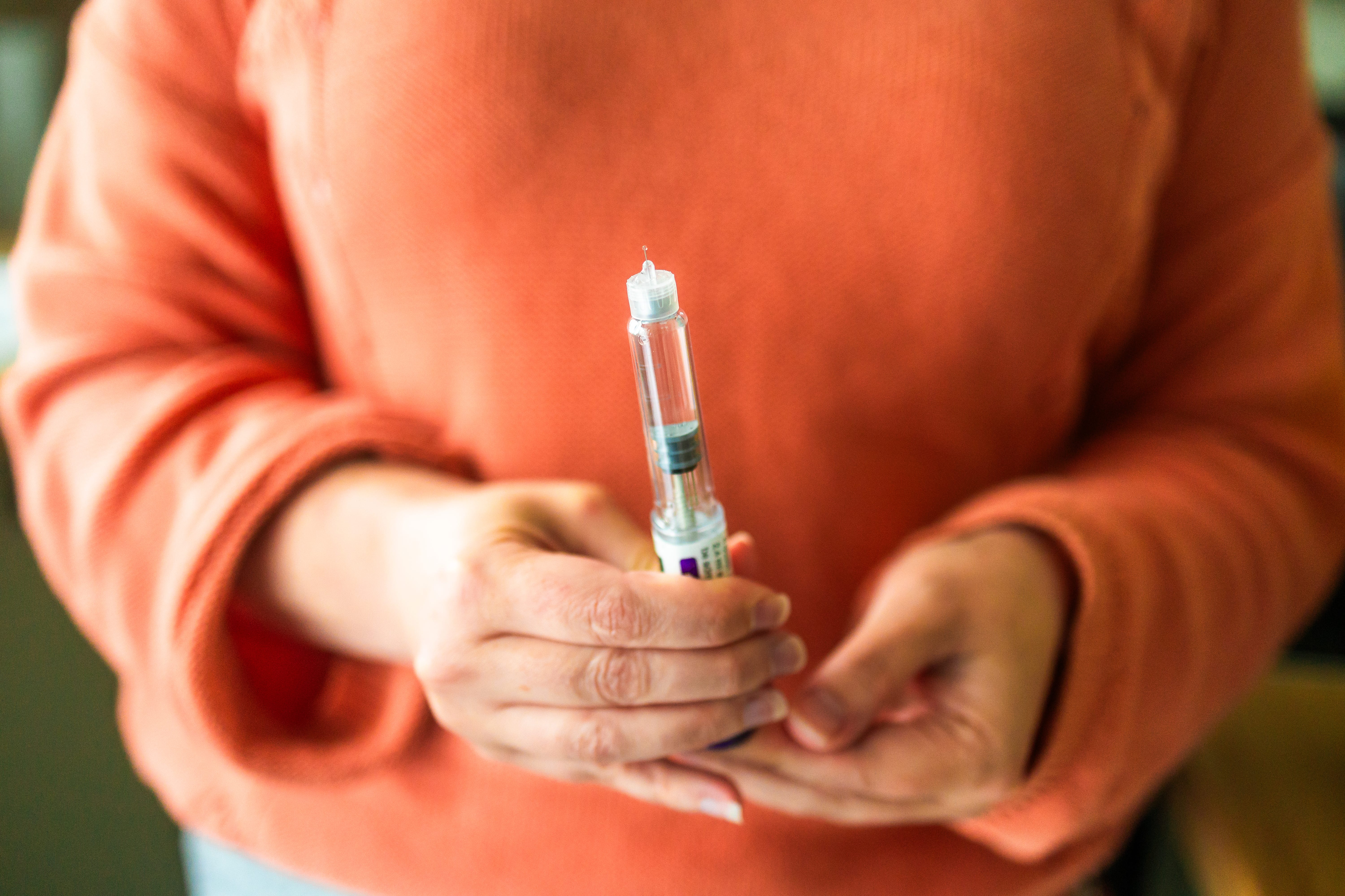 Close up of a woman's hands holding a weight loss injection syringe.