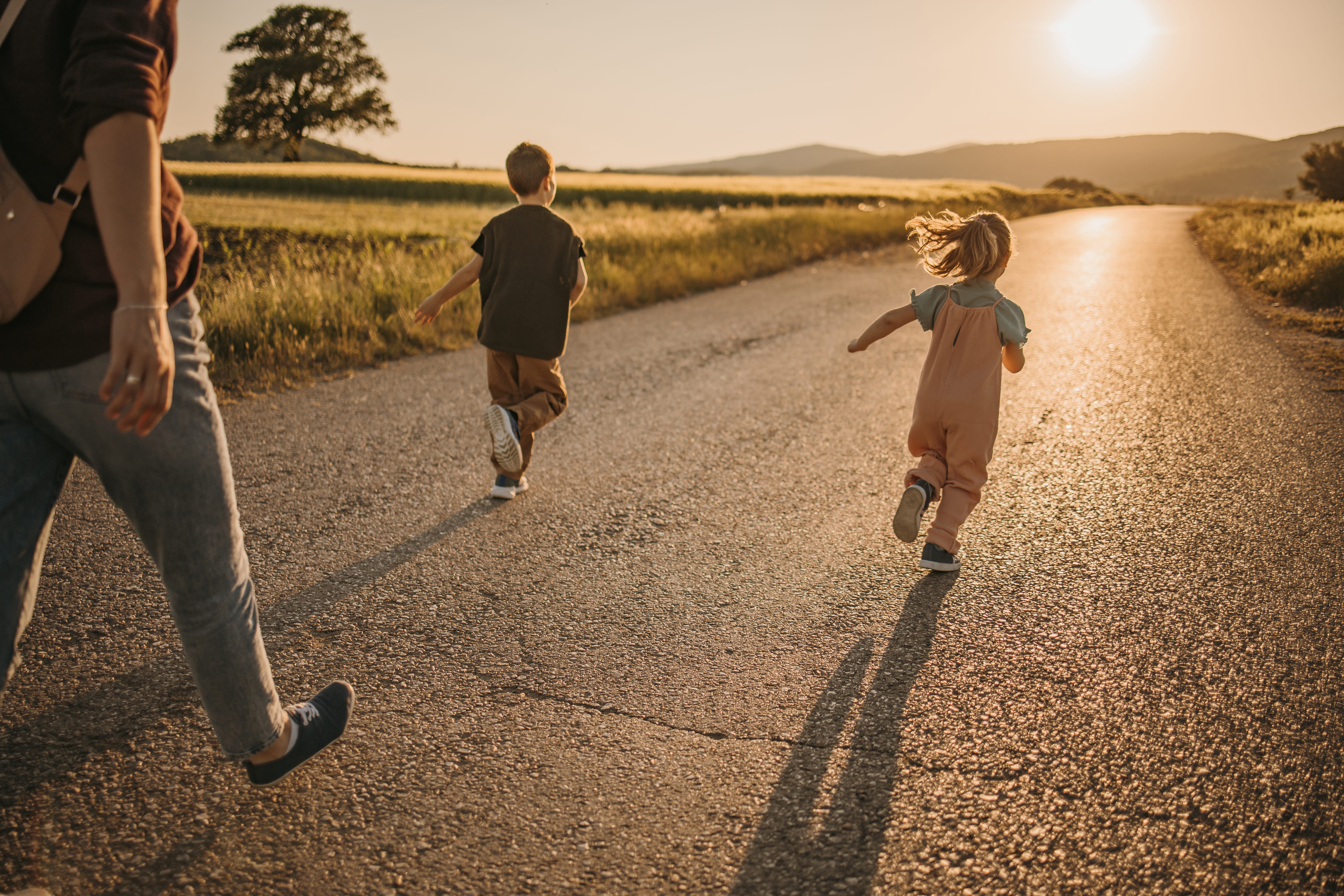 Two kids running in front of their mom