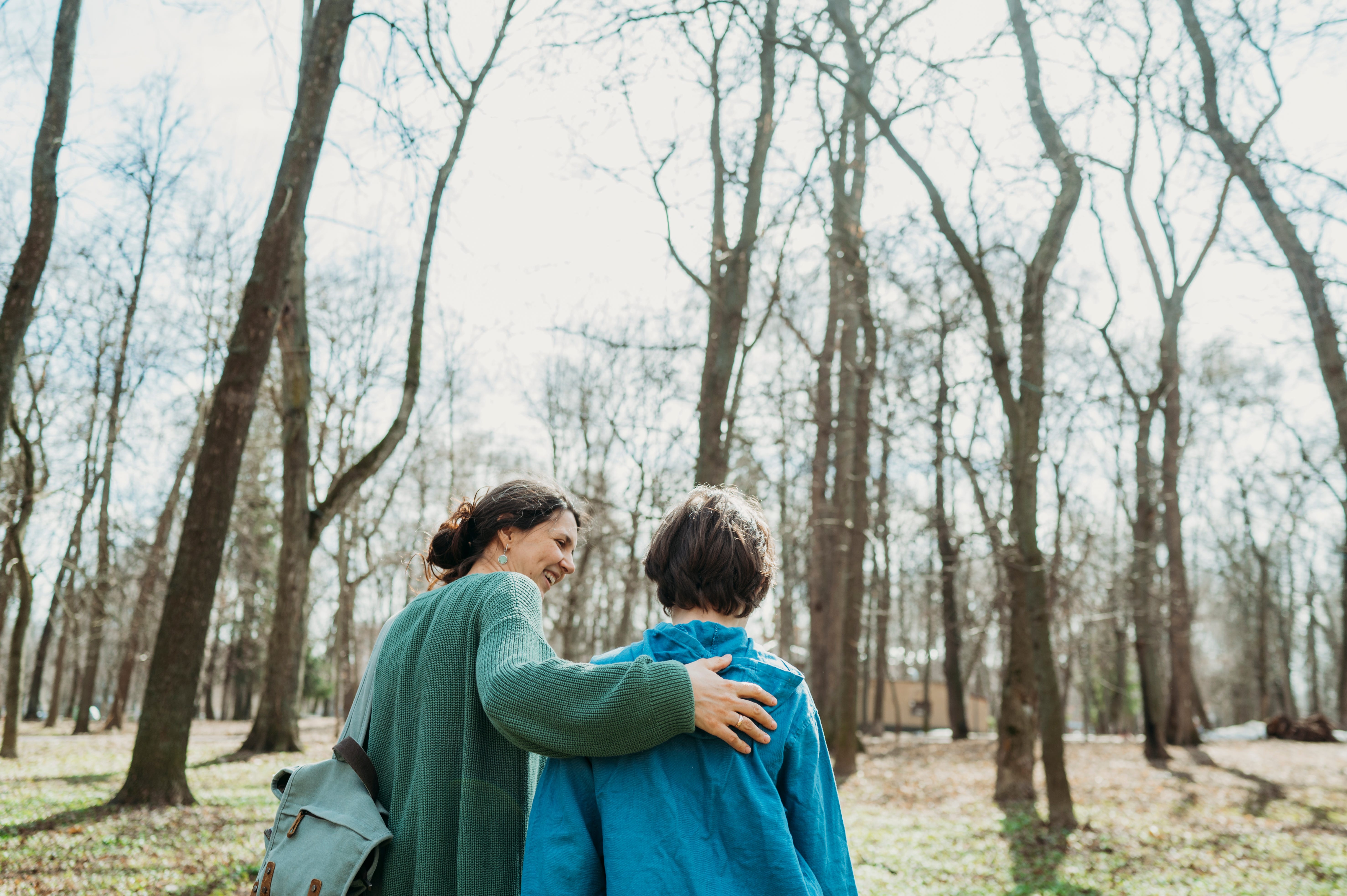 A woman puts her arm around the back of a young boy.