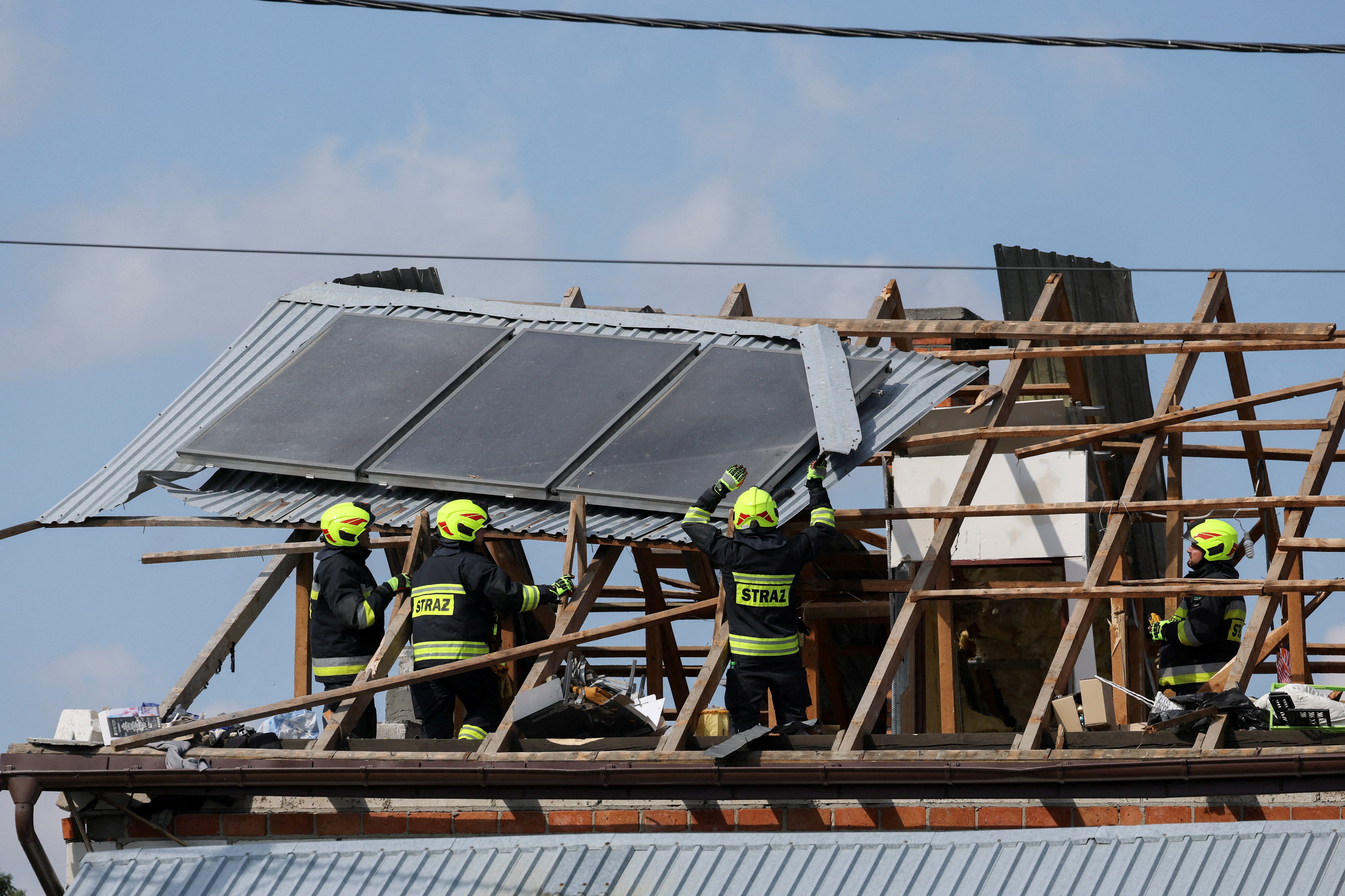 Firefighters work on the destroyed roof of a house, after Russian drones violated Polish airspace during an attack on Ukraine.