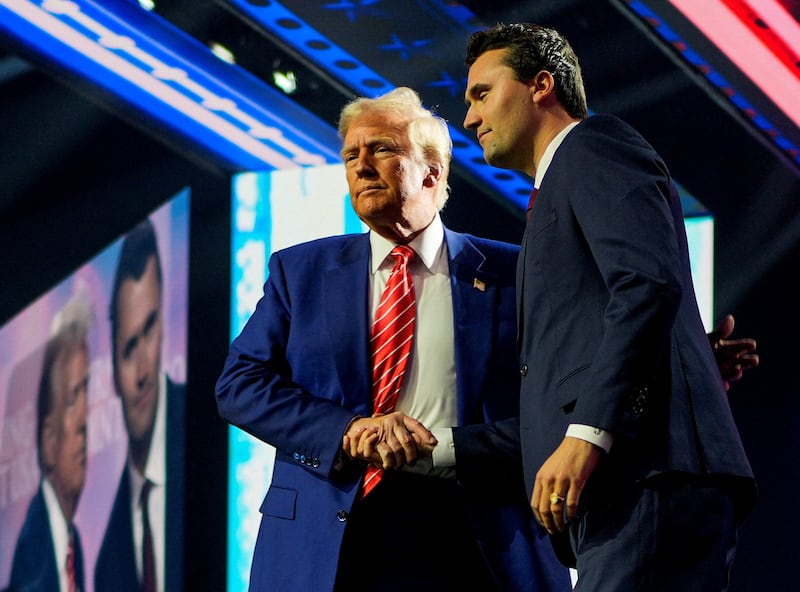 Donald Trump shakes hands with Charlie Kirk, at Turning Point USA's 2024 AmericaFest conference in Phoenix, Arizona on December 22, 2024.