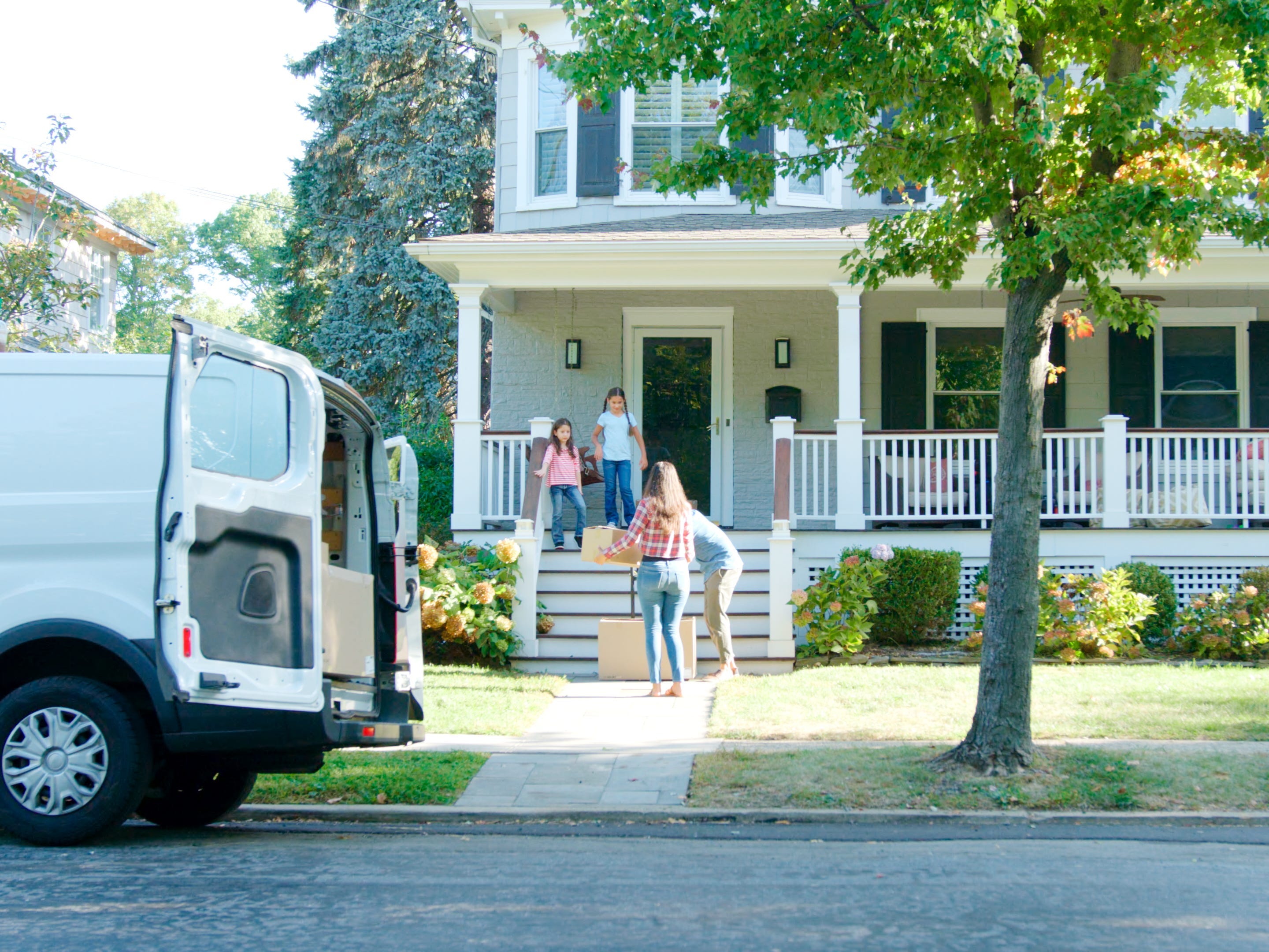 A family unloading items from a moving van to a new home.