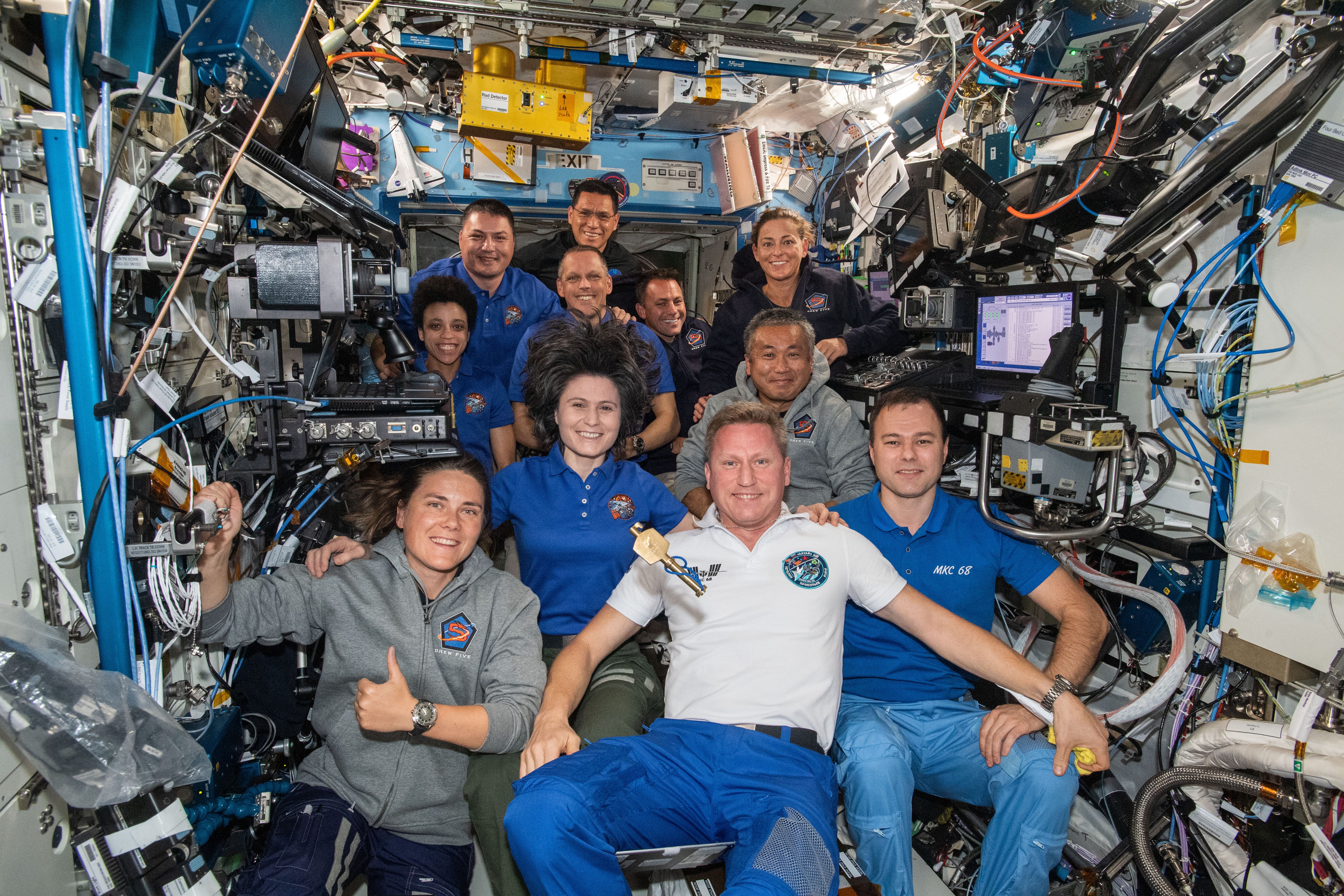 A group of people on the ISS with lots of wires and electronic equipment around