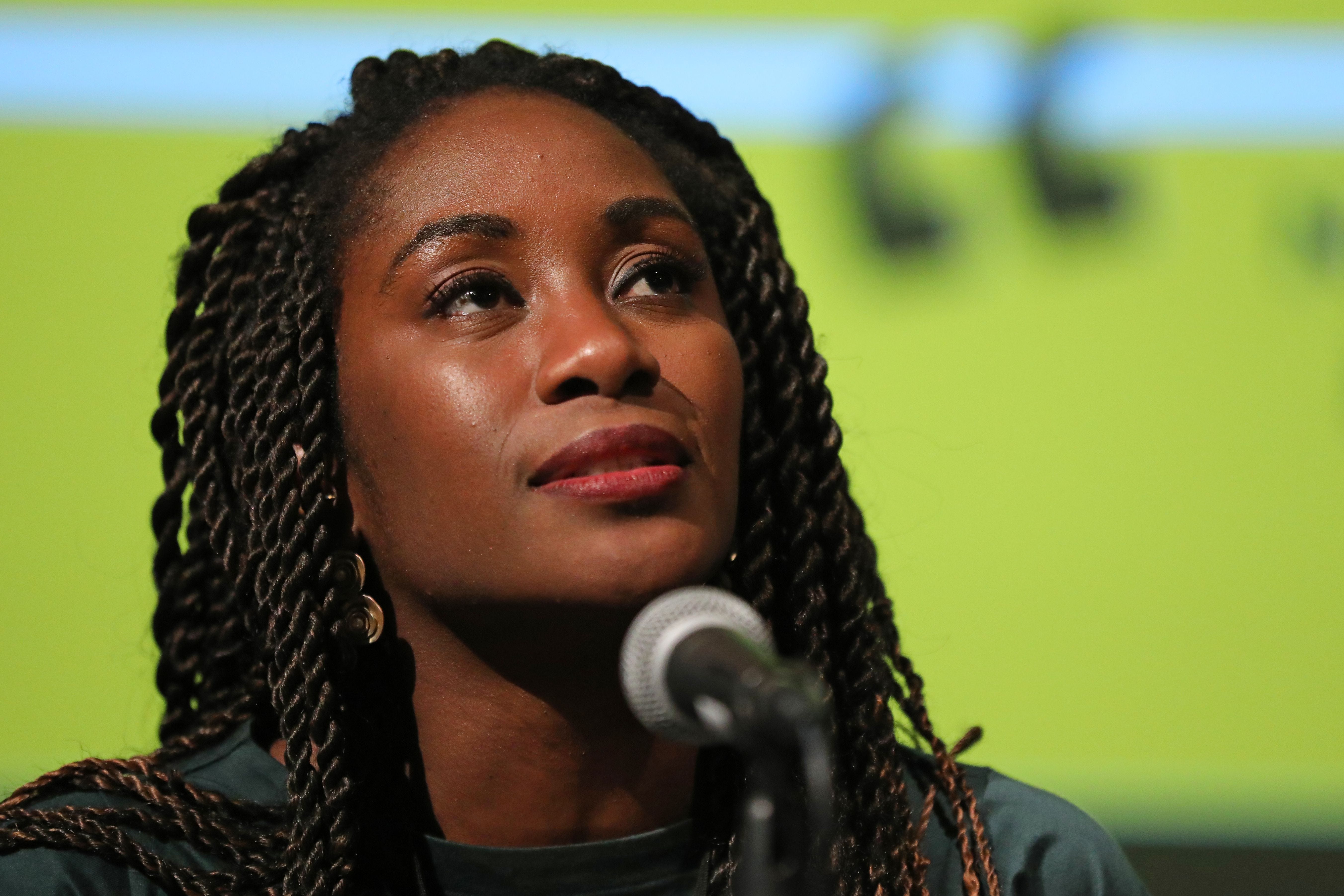 Karen Attiah in front of a microphone on a green background